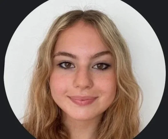 Close-up portrait of a young woman with blonde, wavy hair and a subtle smile, against a white background.
