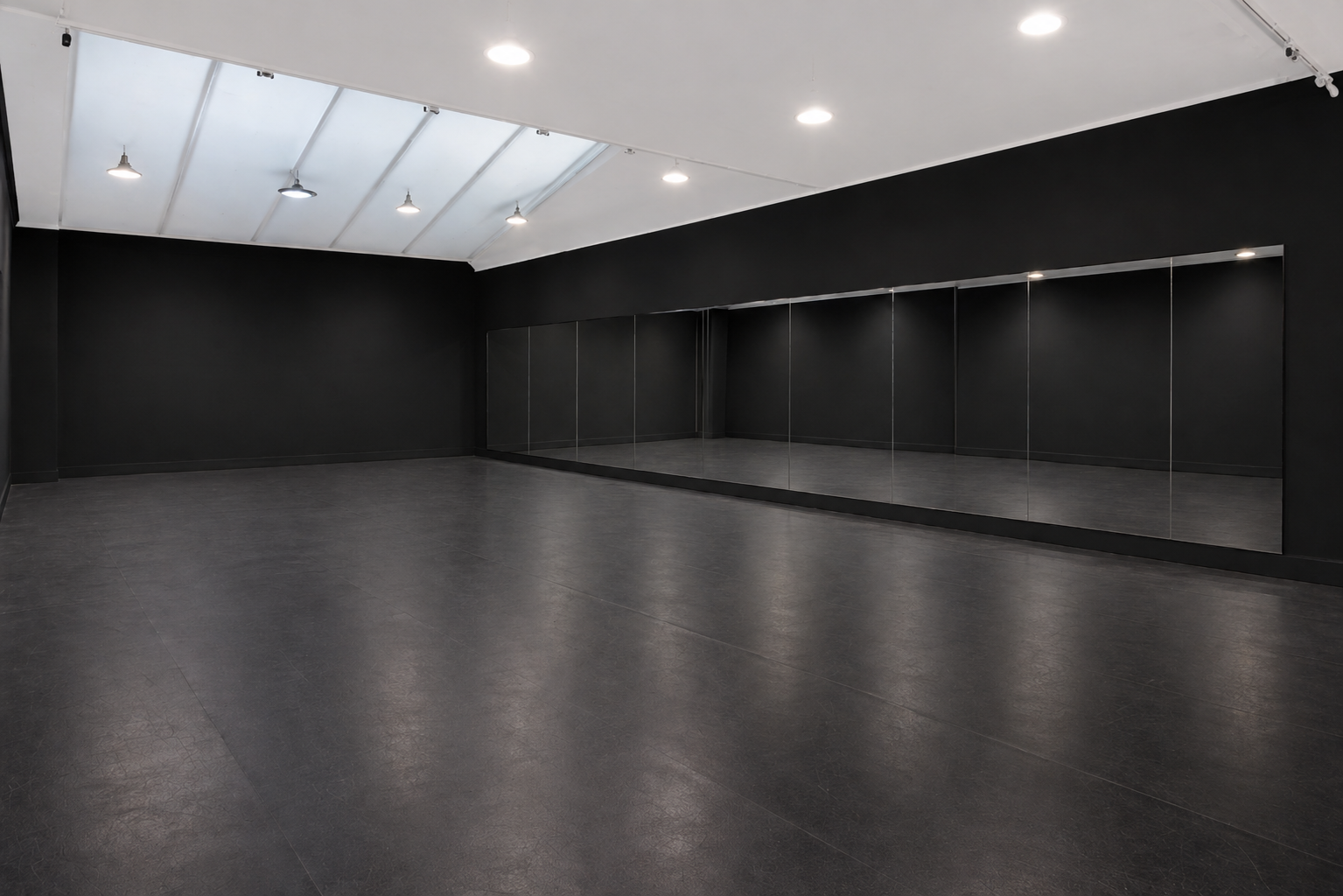 Salle de danse ou studio d'entraînement avec murs noirs, sol sombre, miroirs au mur et éclairage plafond