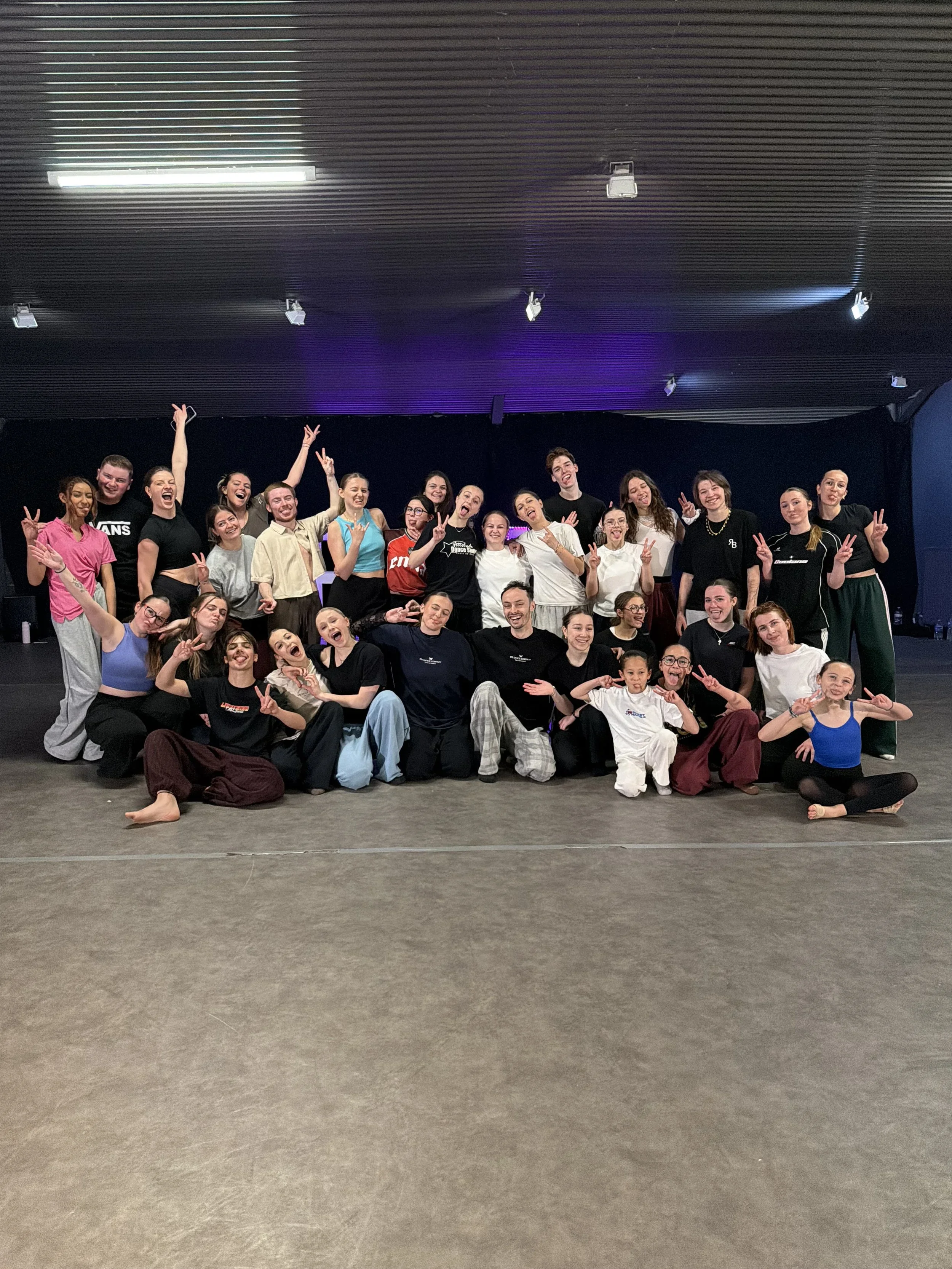 Groupe de personnes souriantes et posant pour une photo dans une salle de danse ou de théâtre.