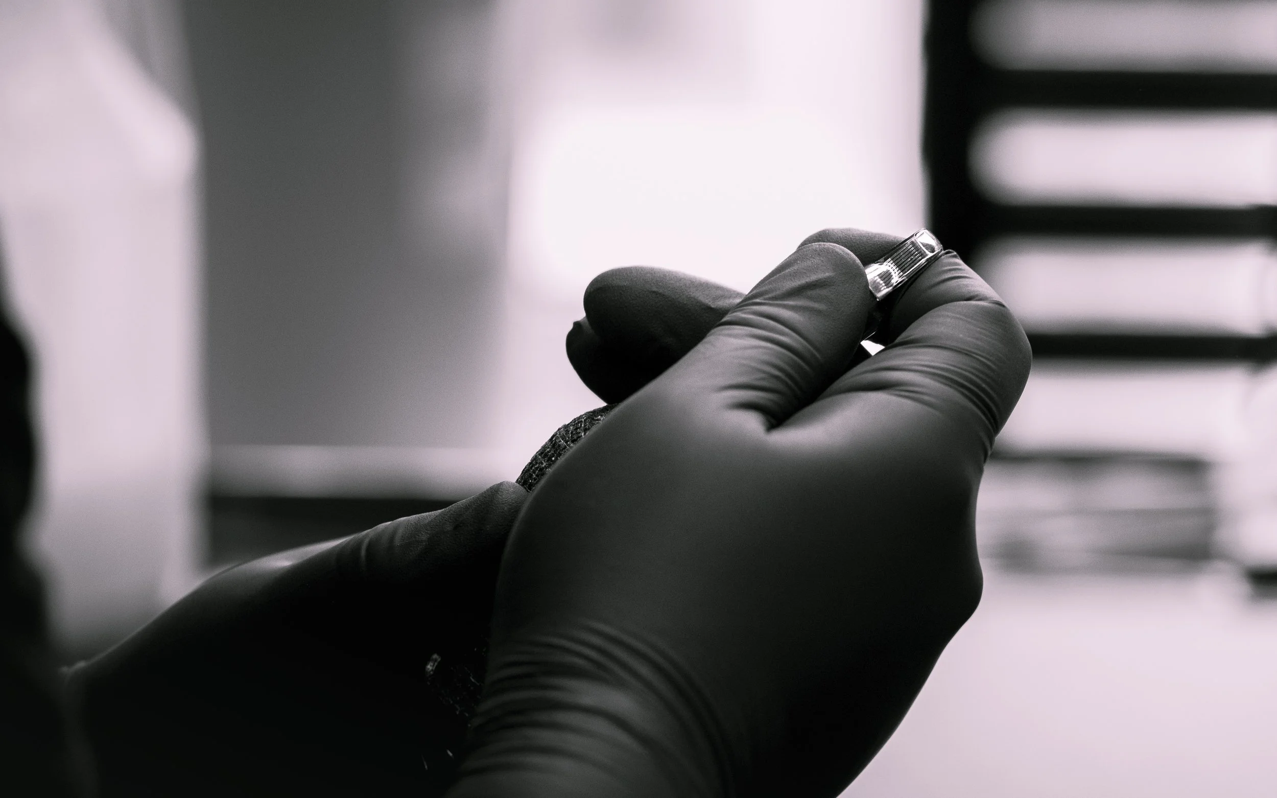A person wearing a black glove holding a ring in their hand, with blurred background.