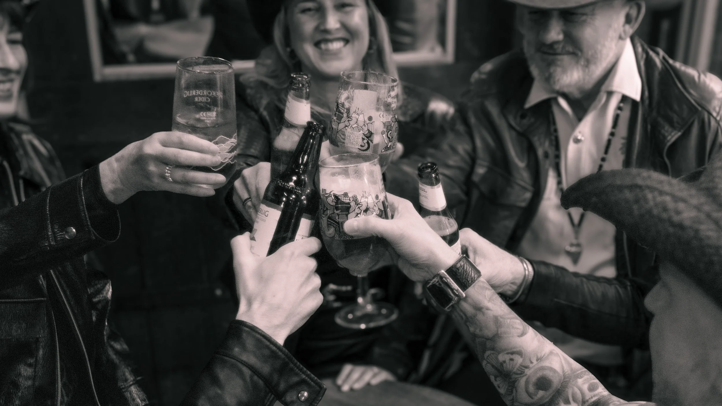 Group of people clinking glasses of beer in a toast at a social gathering.