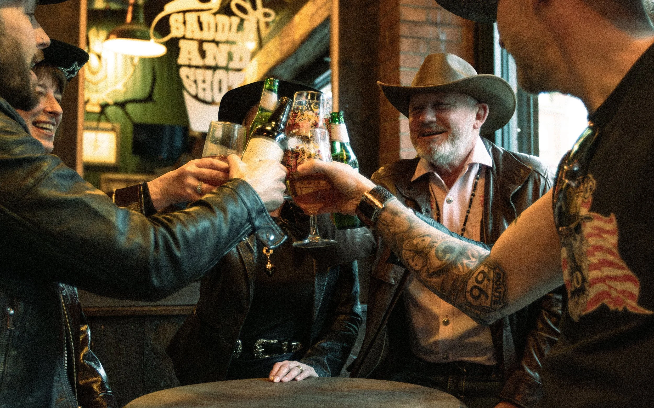 A group of people raising their glasses of beer in a toast at a bar, smiling and having a good time.