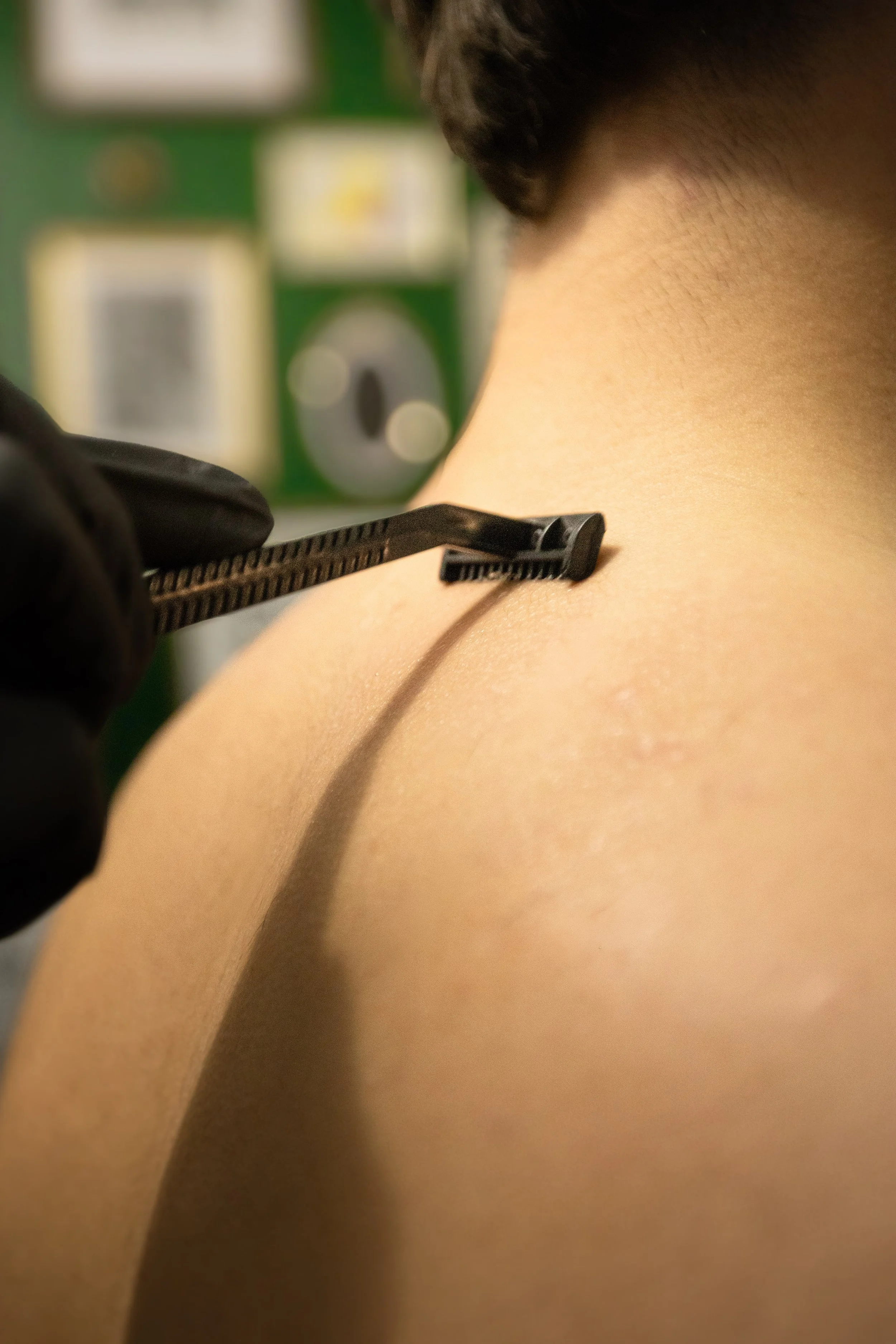 Close-up of a person getting a shave with a razor blade on their neck.