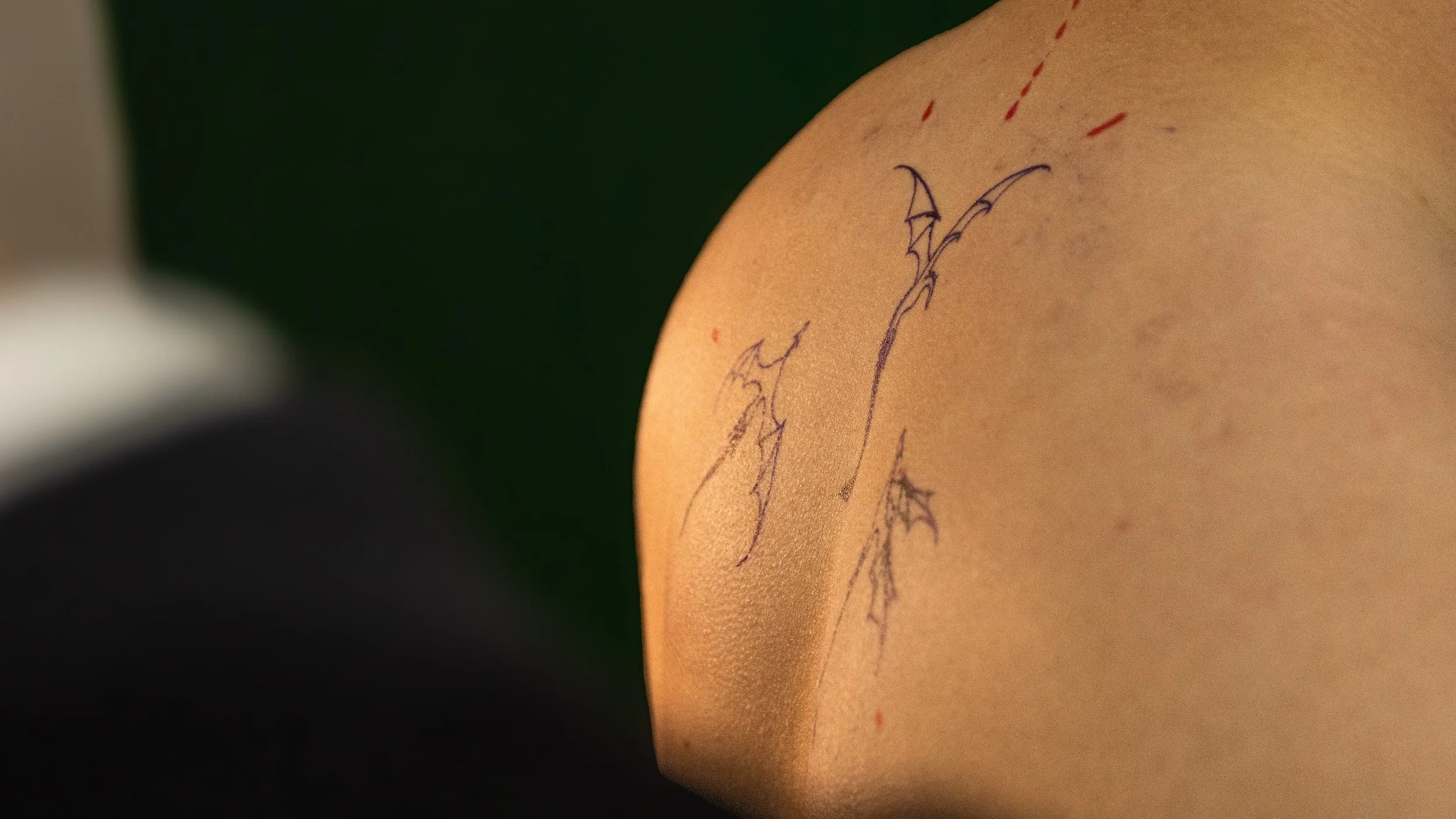 A close-up of a person's shoulder with a temporary tattoo of a dragon on their skin.