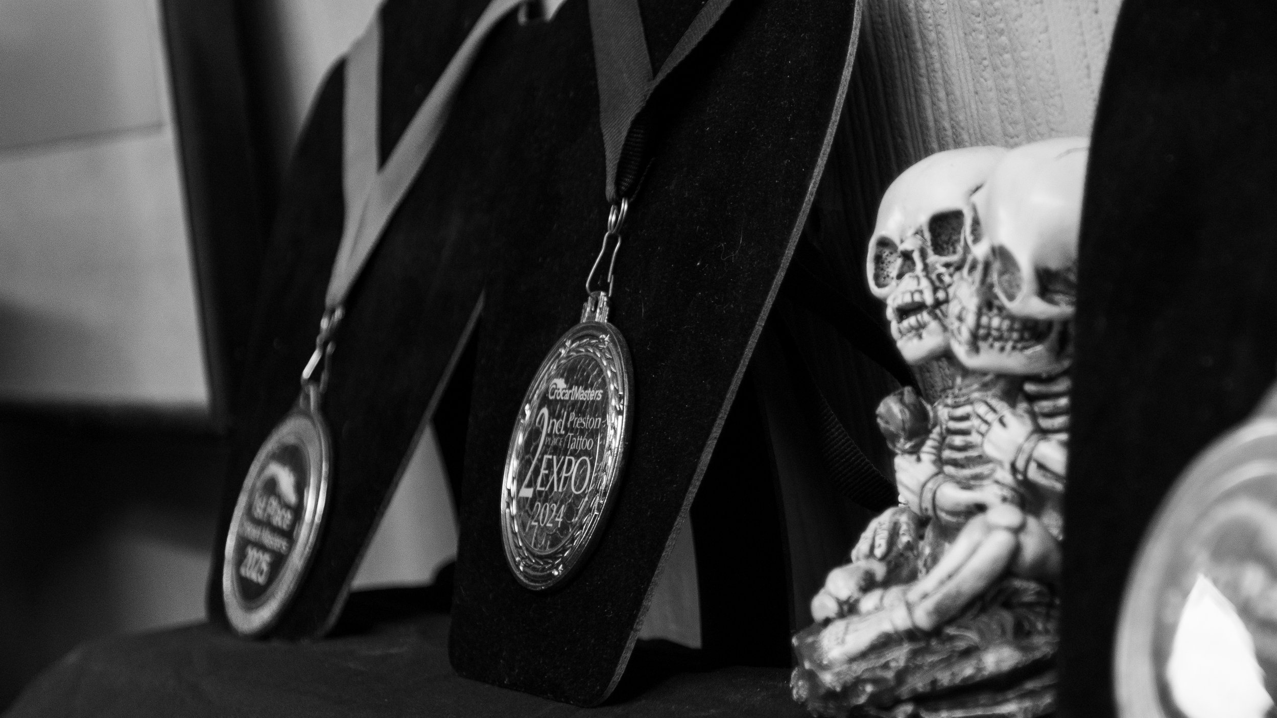 Black and white photograph of medals hanging around a person's neck with a skeletal figurine sitting beside them.