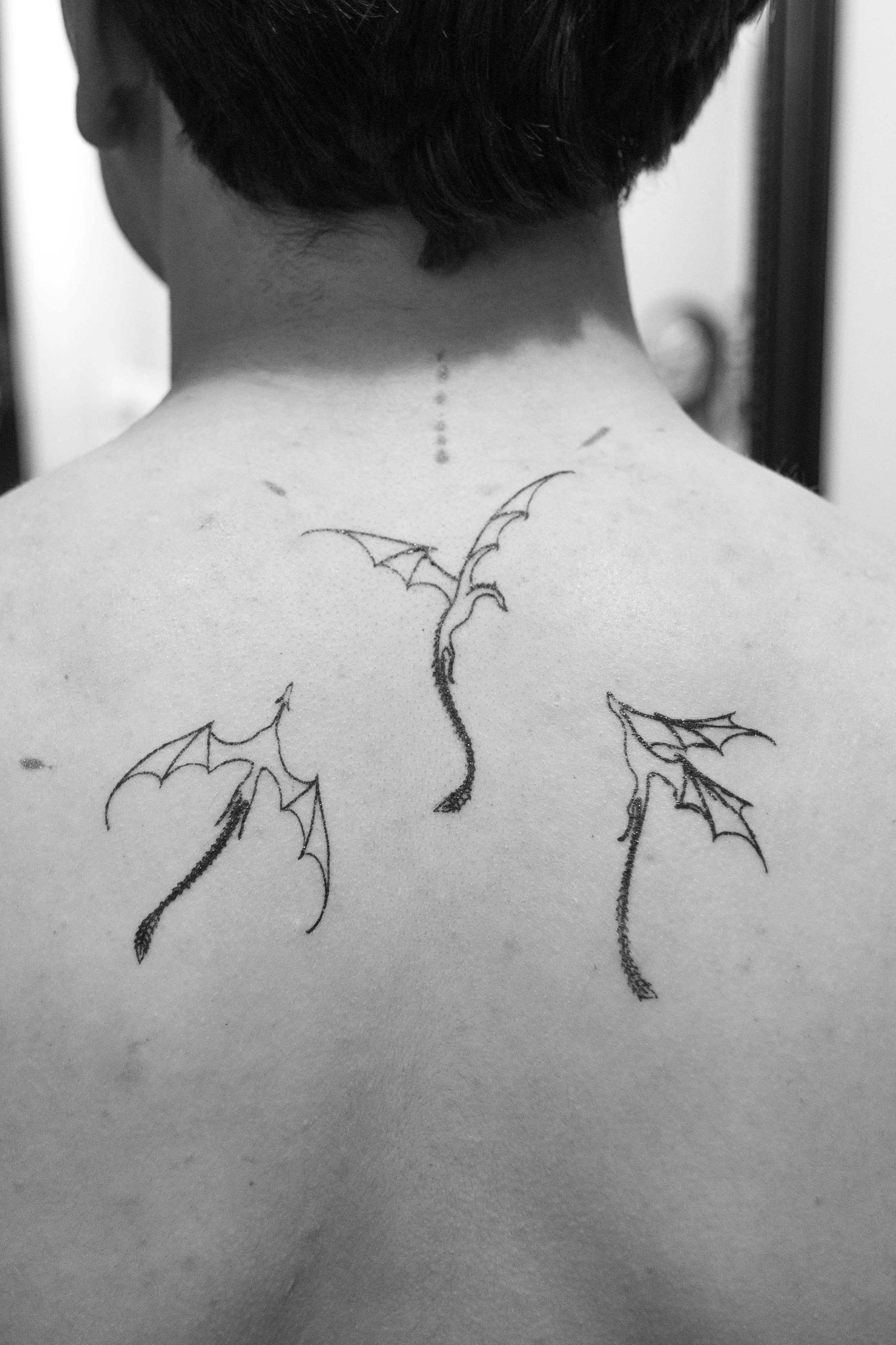 Back of a person's neck and shoulders with a dragon tattoo.