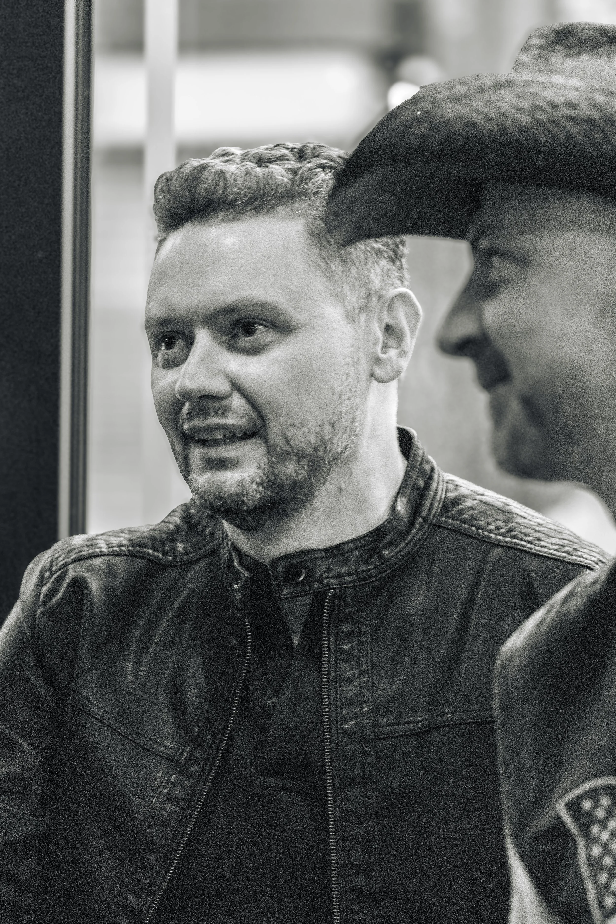 Close-up of two men engaged in conversation, one smiling and the other listening, in a casual setting.