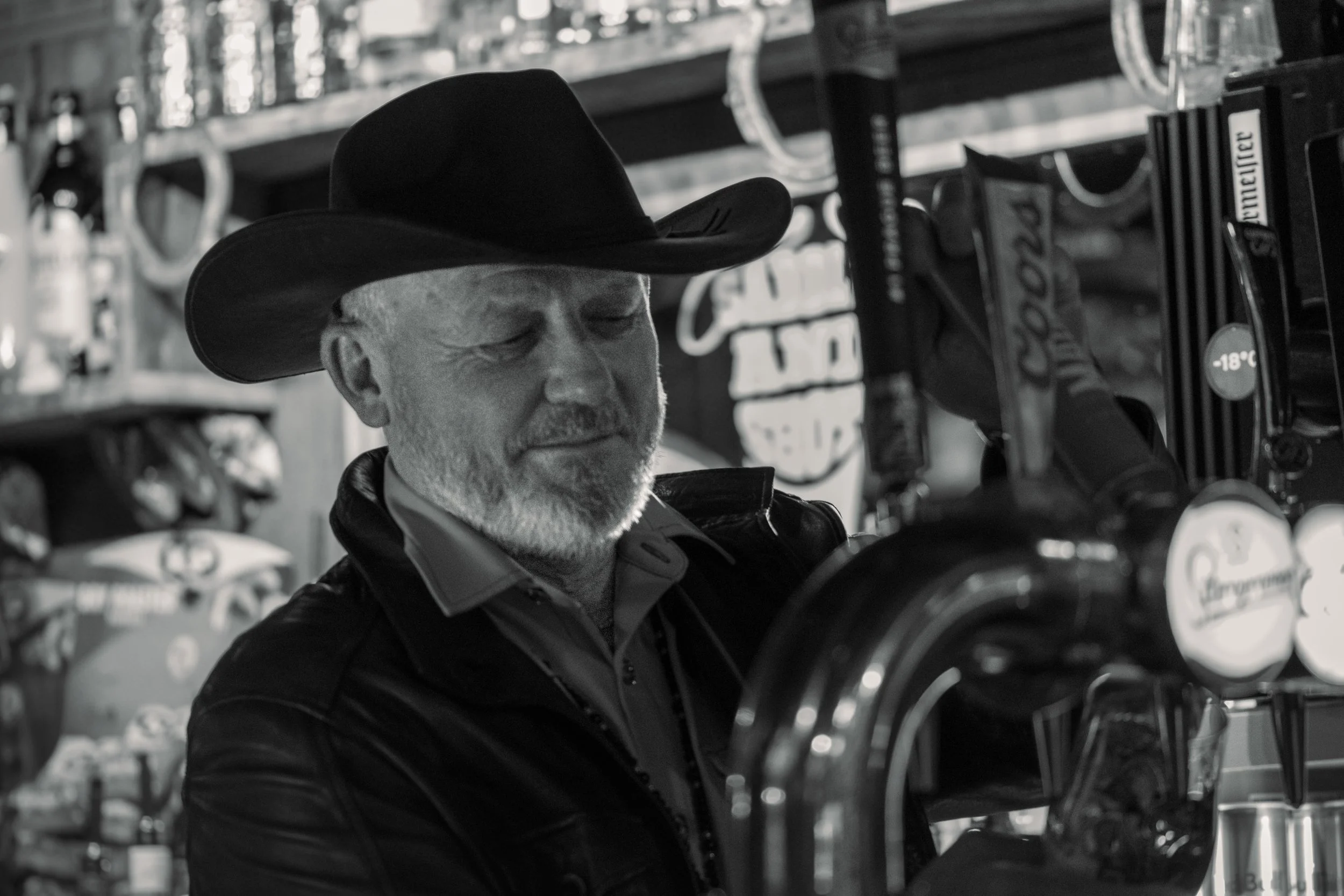 A man wearing a cowboy hat in a store aisle with shelves of products behind him.