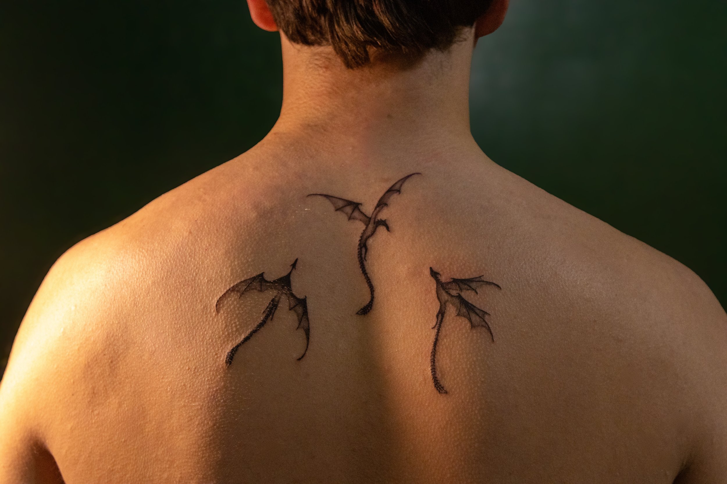 Back of a person with Batman-themed butterfly tattoo near shoulder.