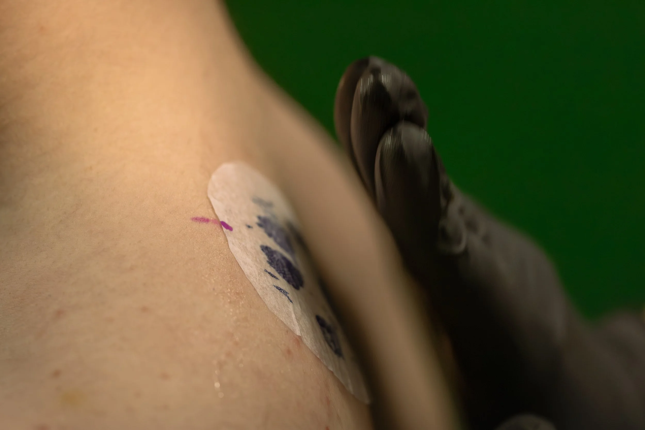 Close-up of a tattoo needle applying ink to skin.