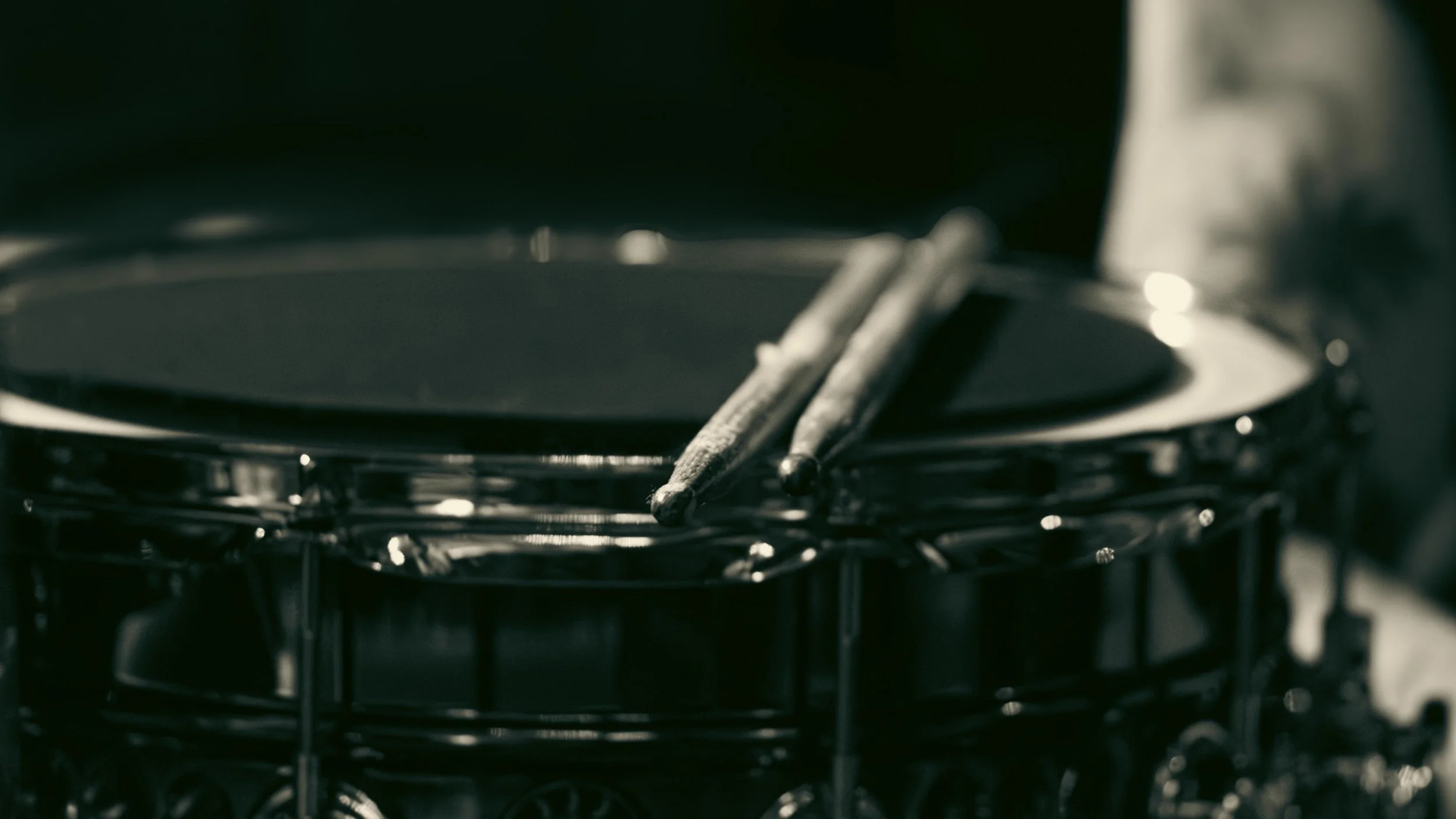 Close-up of a snare drum with drumsticks resting on top.