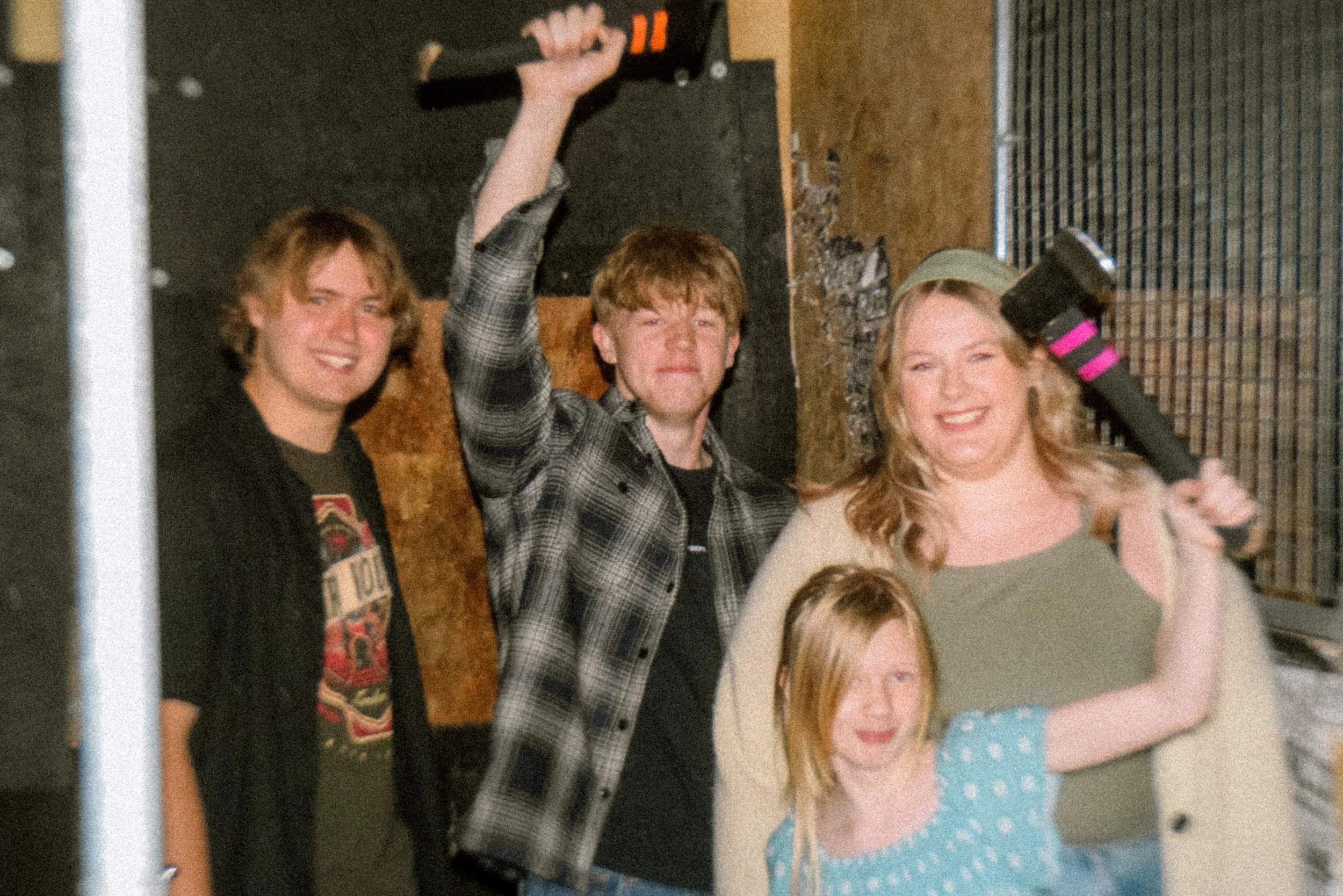 A family in an axe throwing lane, posing for the camera after having fun