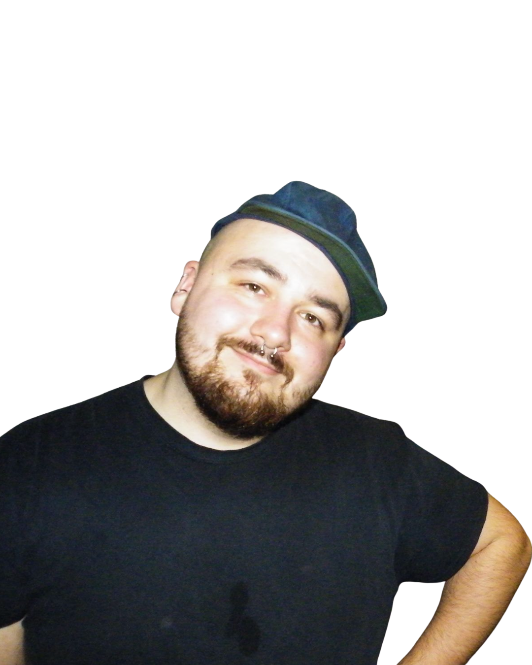 A young man with a beard and septum piercing, wearing a black shirt and a dark hat, smiling and posing with his arm bent, against a black background.