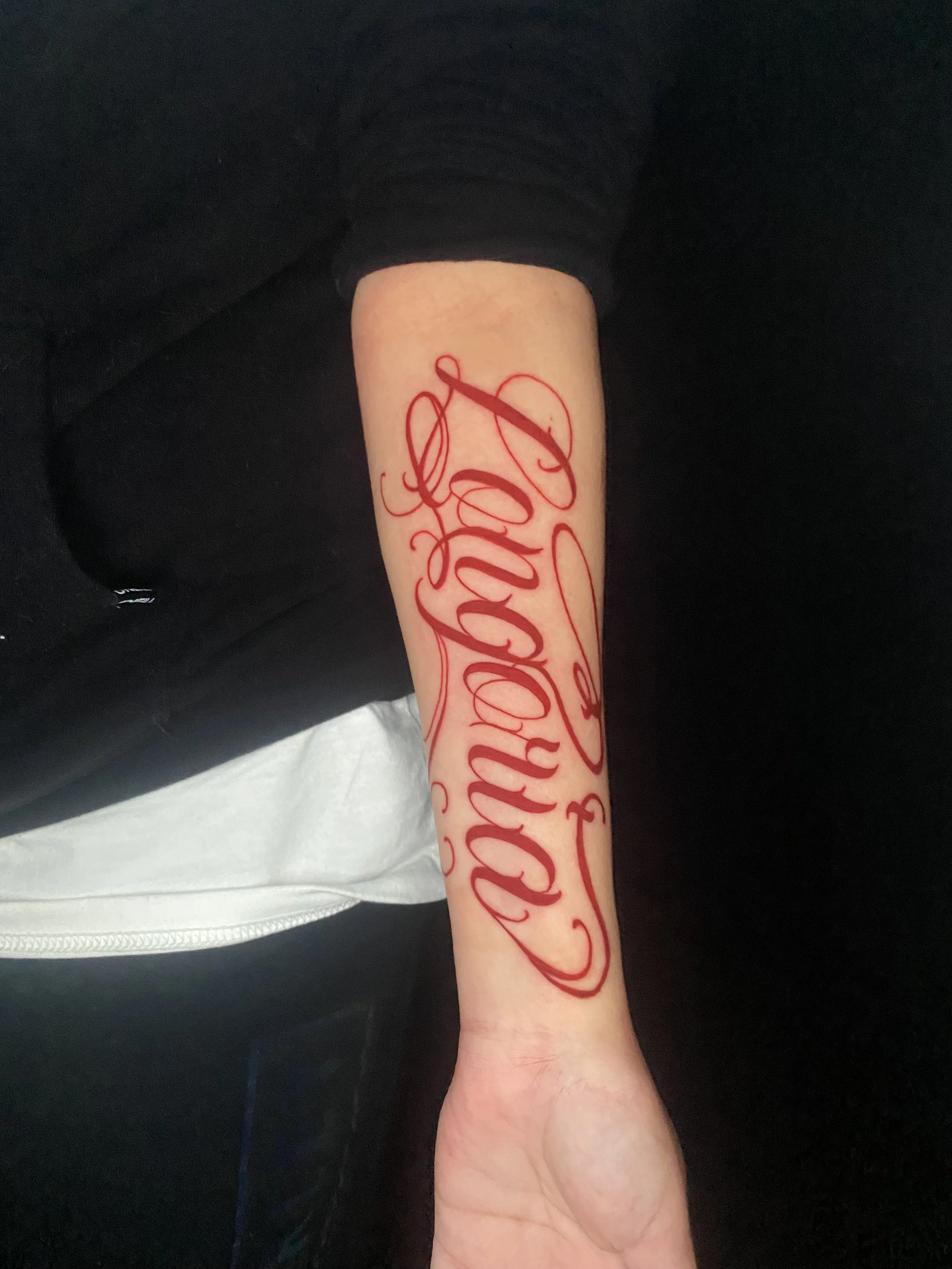 A person's arm with a red tattoo that says 'Hope' in cursive script.