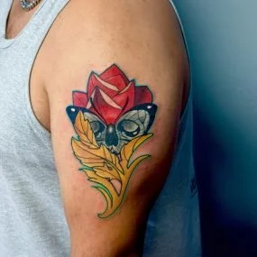 Colorful tattoo of a red rose with a bee and yellow leaves on a person's upper arm.
