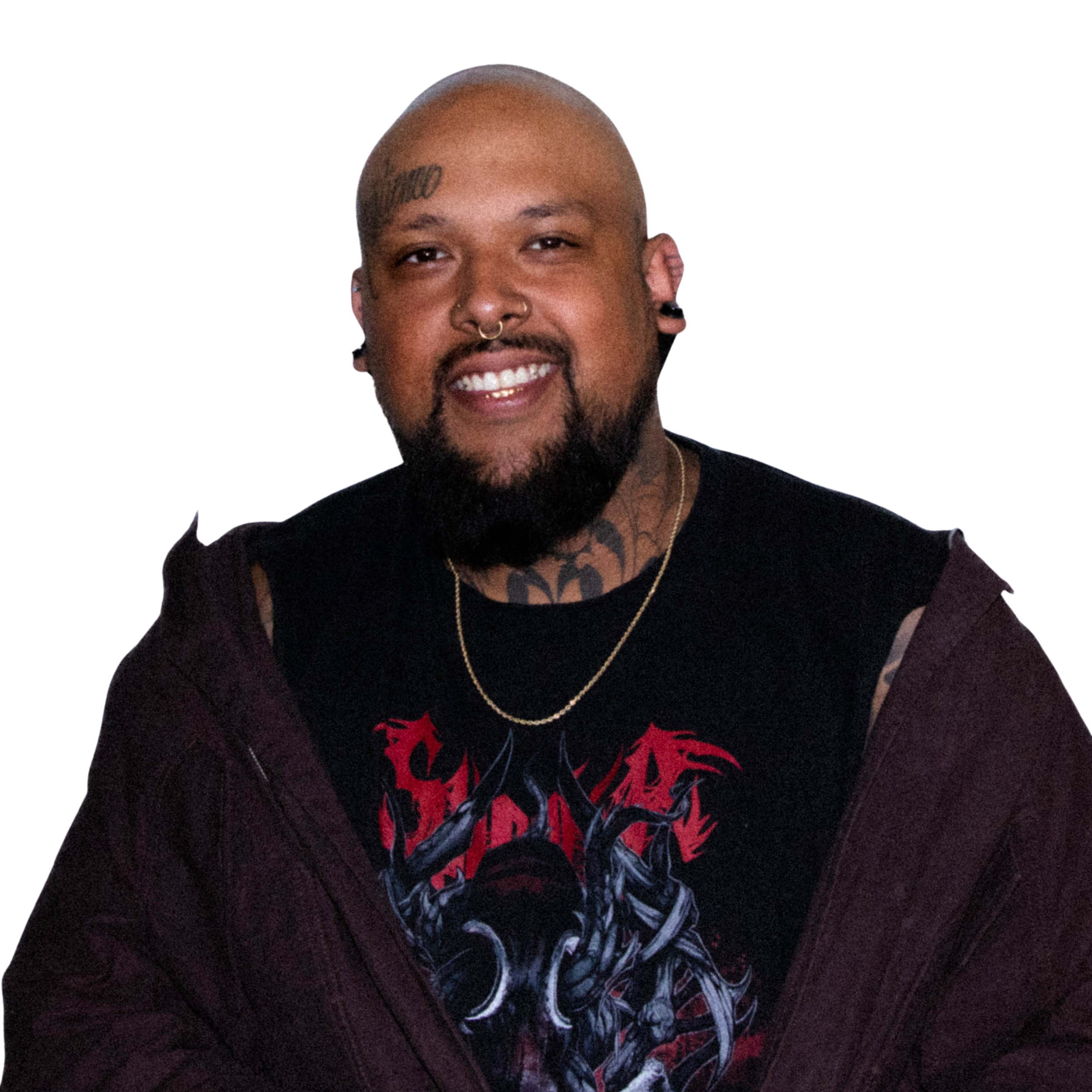 A smiling man with a shaved head, tattoos, and earrings, wearing a black shirt with red and blue graphic design, and a gold chain necklace.