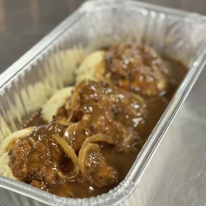 Beef stew with potatoes and gravy in a metal food container.