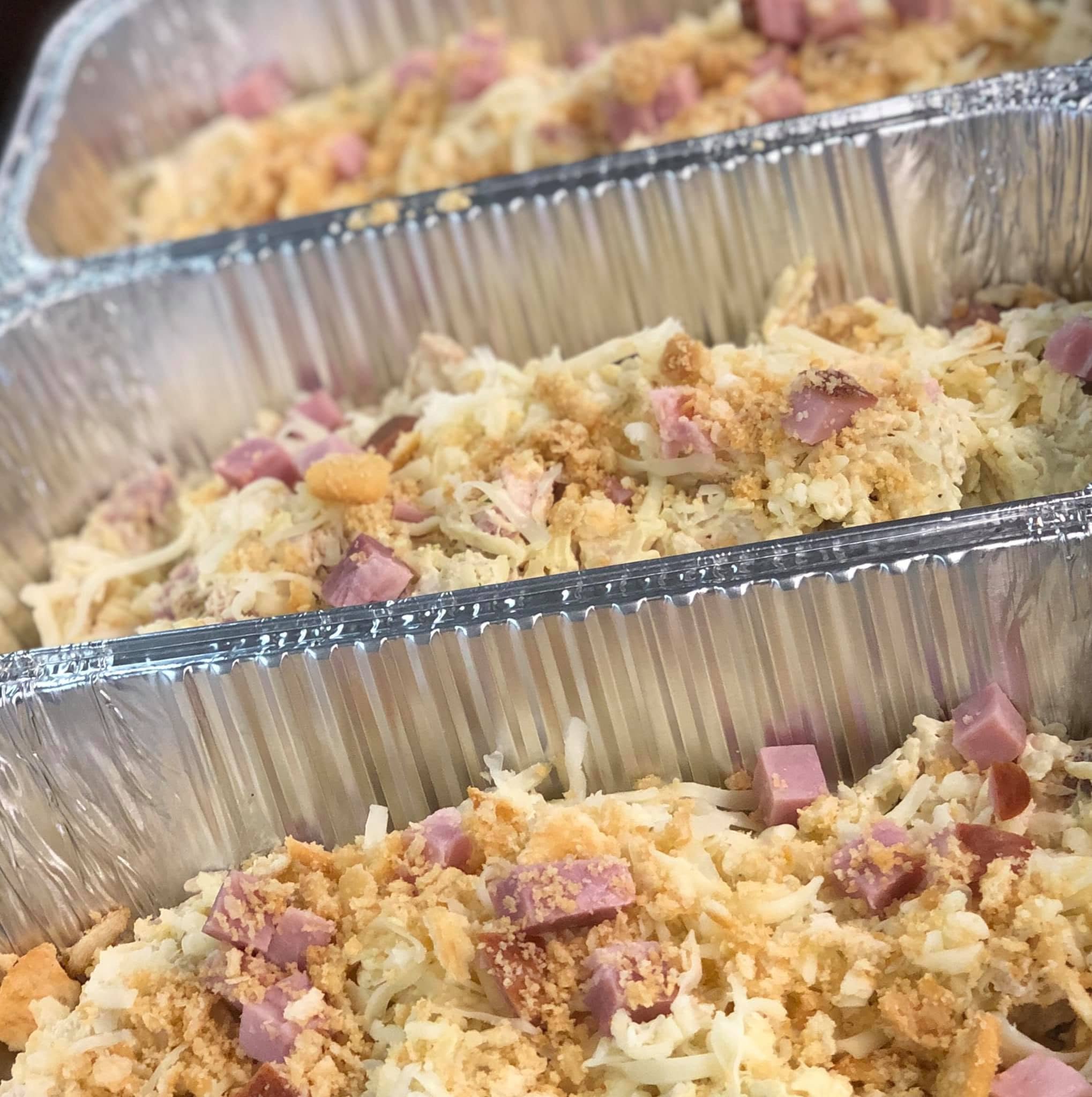 Close-up view of a foil tray containing a mix of chopped ham, shredded cheese, and breadcrumbs.
