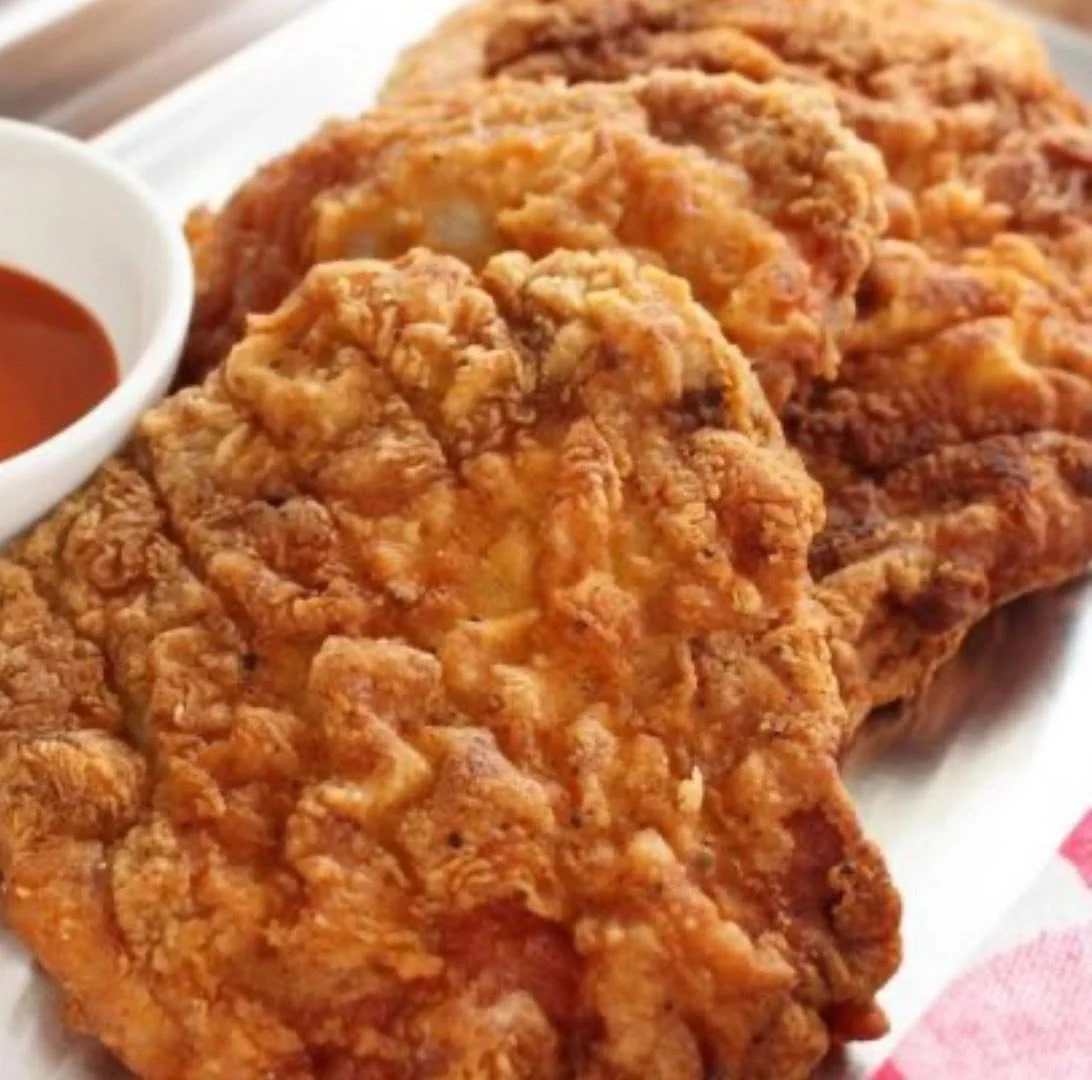 Three pieces of fried chicken with a side of dipping sauce
