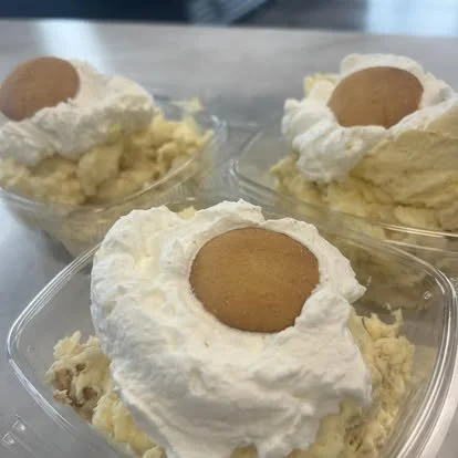Three dessert cups filled with banana pudding, topped with whipped cream and a cookie.