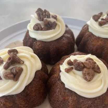 Close-up of four chocolate cupcakes topped with swirls of vanilla frosting and chocolate sprinkles.