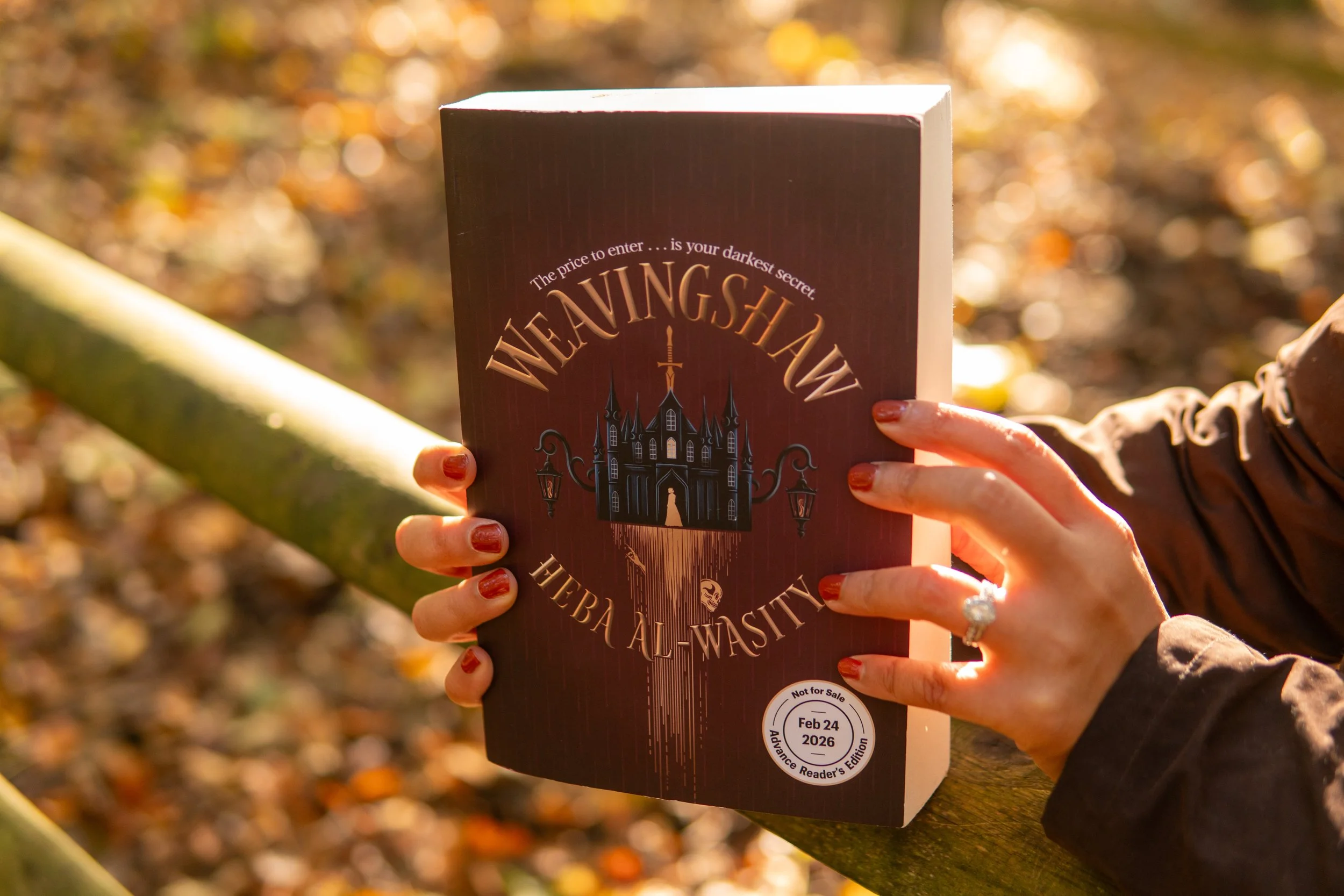 Person holding a book titled 'Wewingshawn' outdoors with autumn leaves in the background.