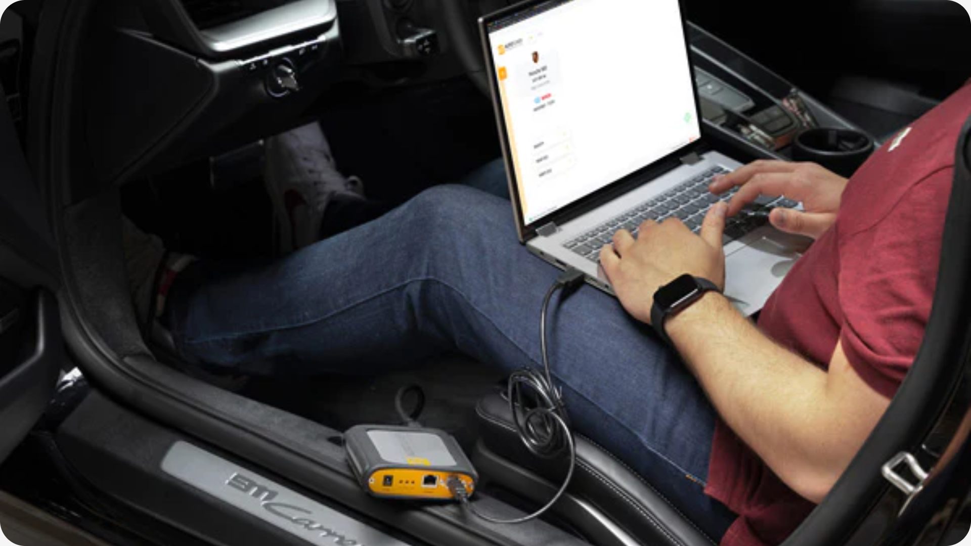 Persoon die op de bestuurderstoel zit en daar zit hij met een laptop de software van de ECU/TCU aan te passen.