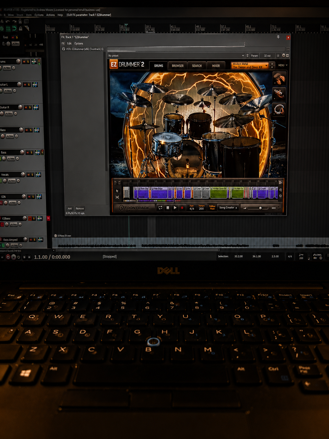 Computer screen displaying music production software with a drum set graphic background, surrounded by lightning effects, and a keyboard in the foreground.