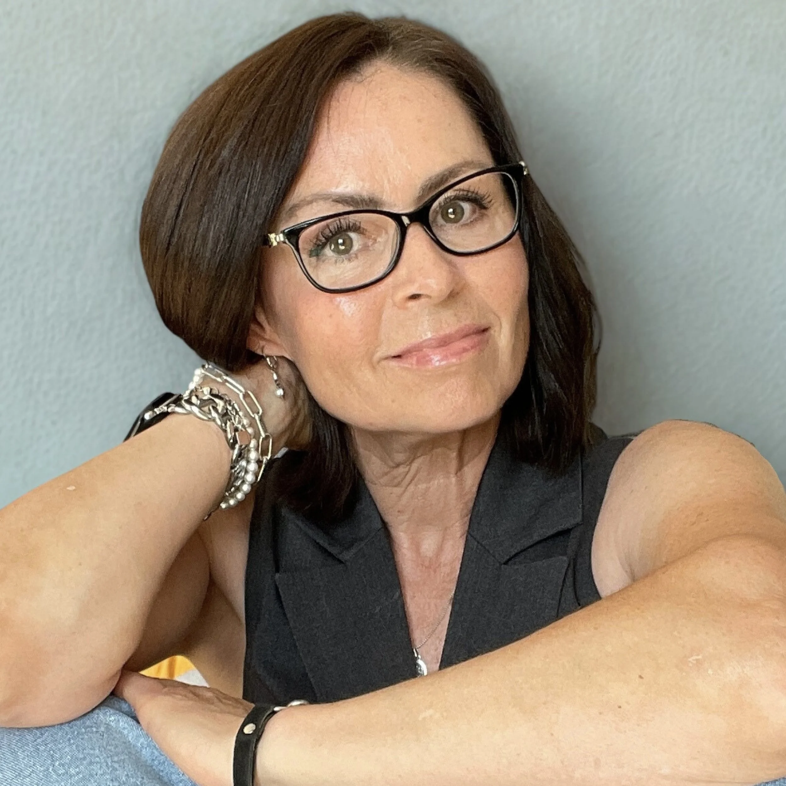 Portrait of Tracey Walker wearing black framed glasses and smiling.