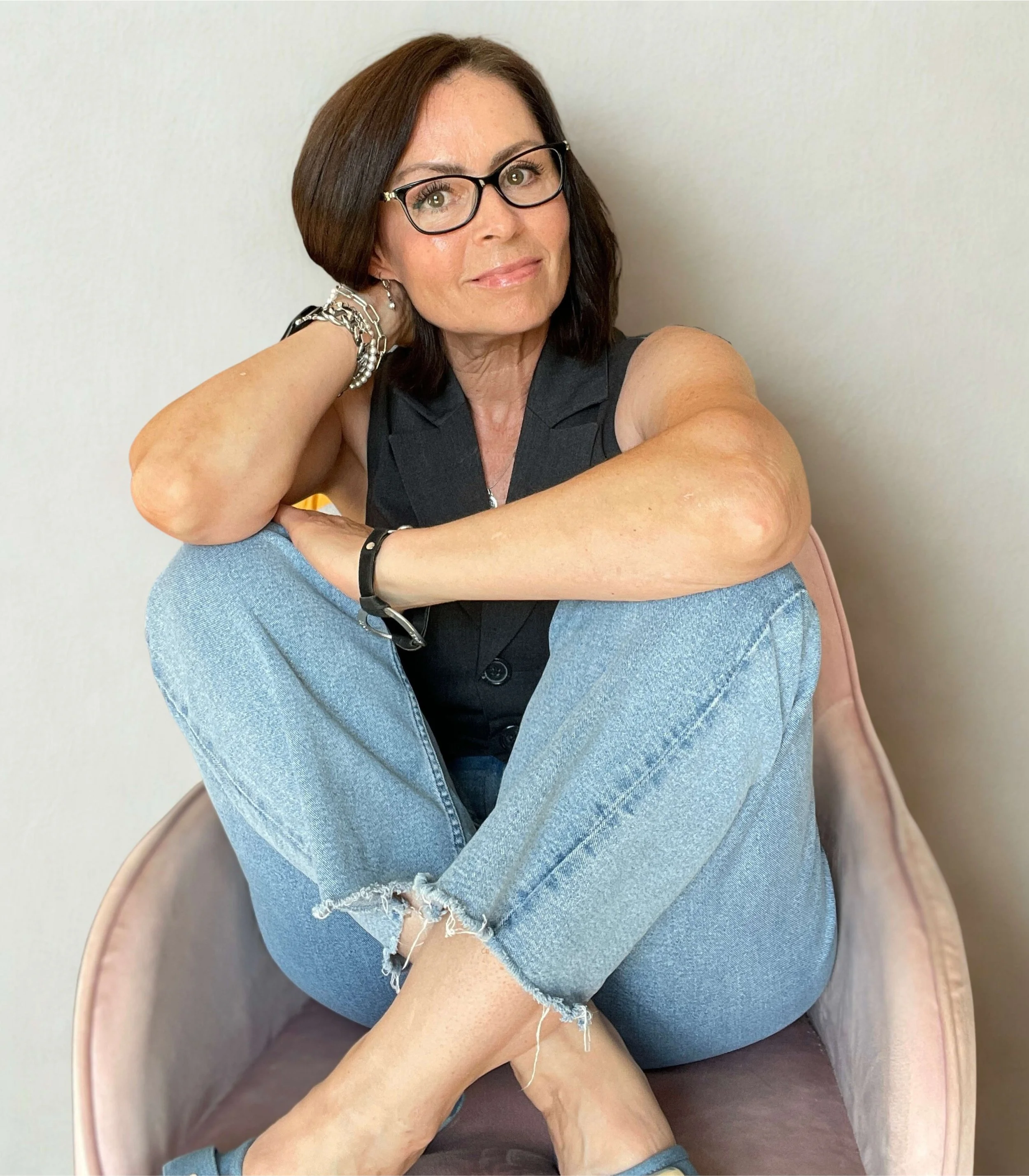 Tracey Walker sitting on a pink chair and smiling at the camera.