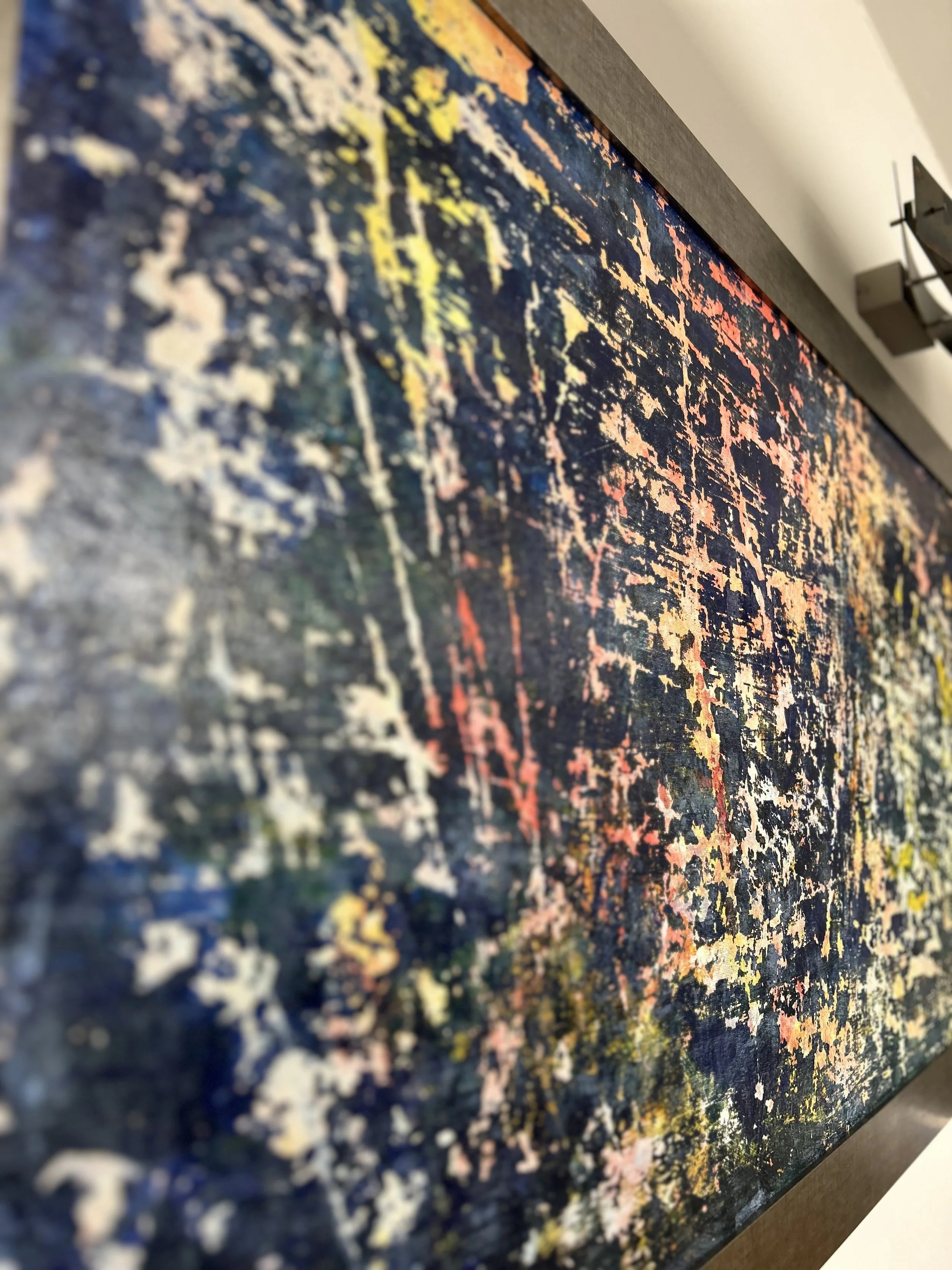 Close-up of an abstract colorful painting with a dark background, splashes and patterns in yellow, pink, blue, orange, and white strokes.