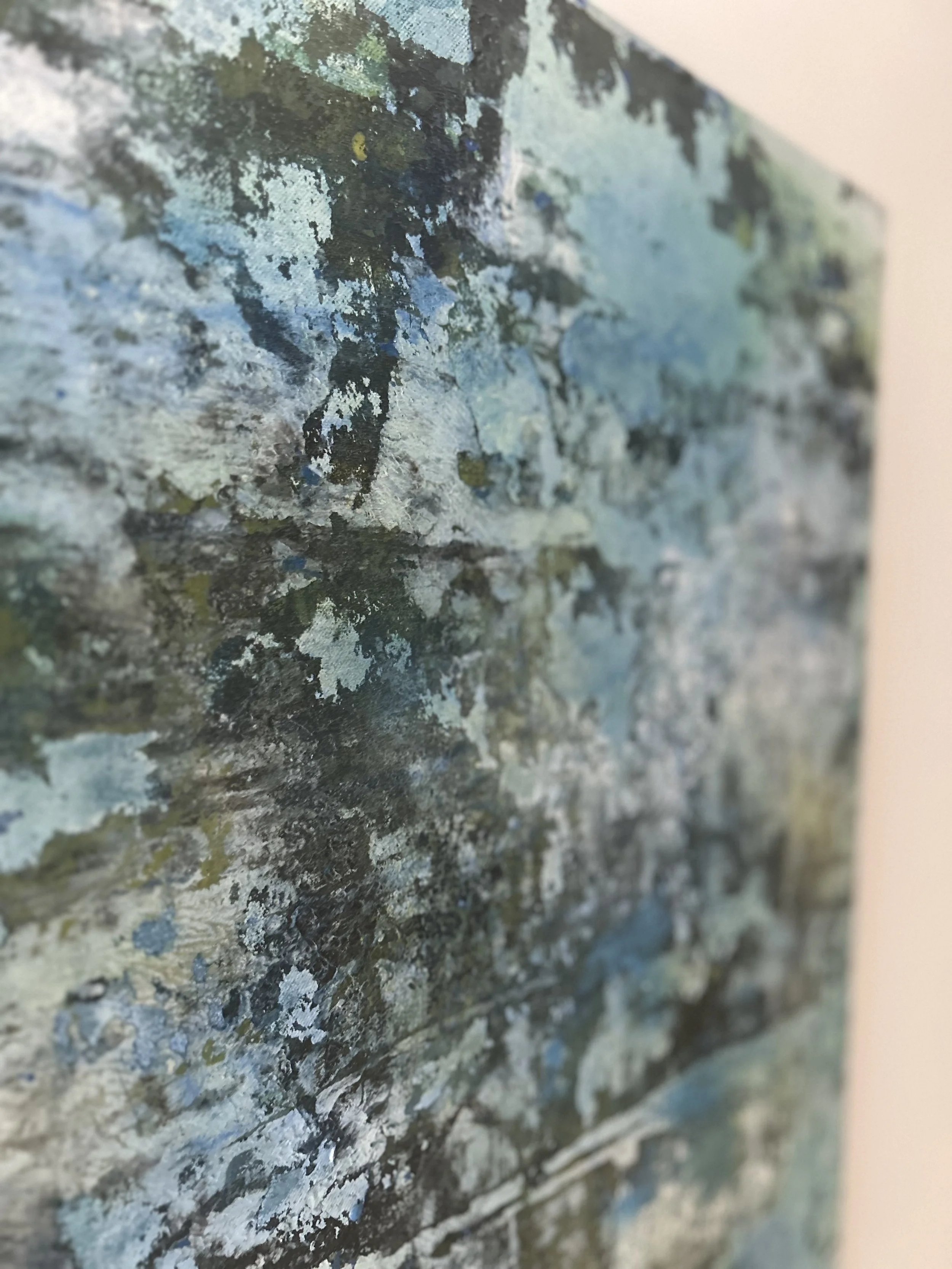 Close-up of a textured, weathered surface with layers of paint peeling off, revealing the underlying material in various shades of blue, gray, and white.