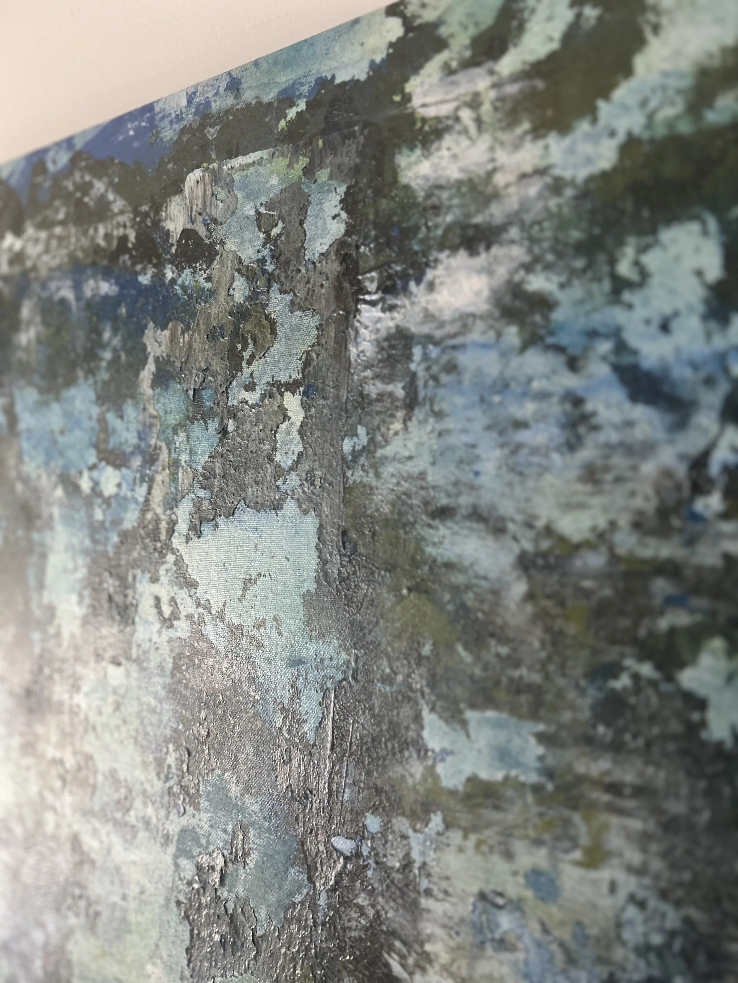 Close-up image of peeling paint on a wall with layers of various colors including blue, gray, and white, revealing the textured surface beneath.