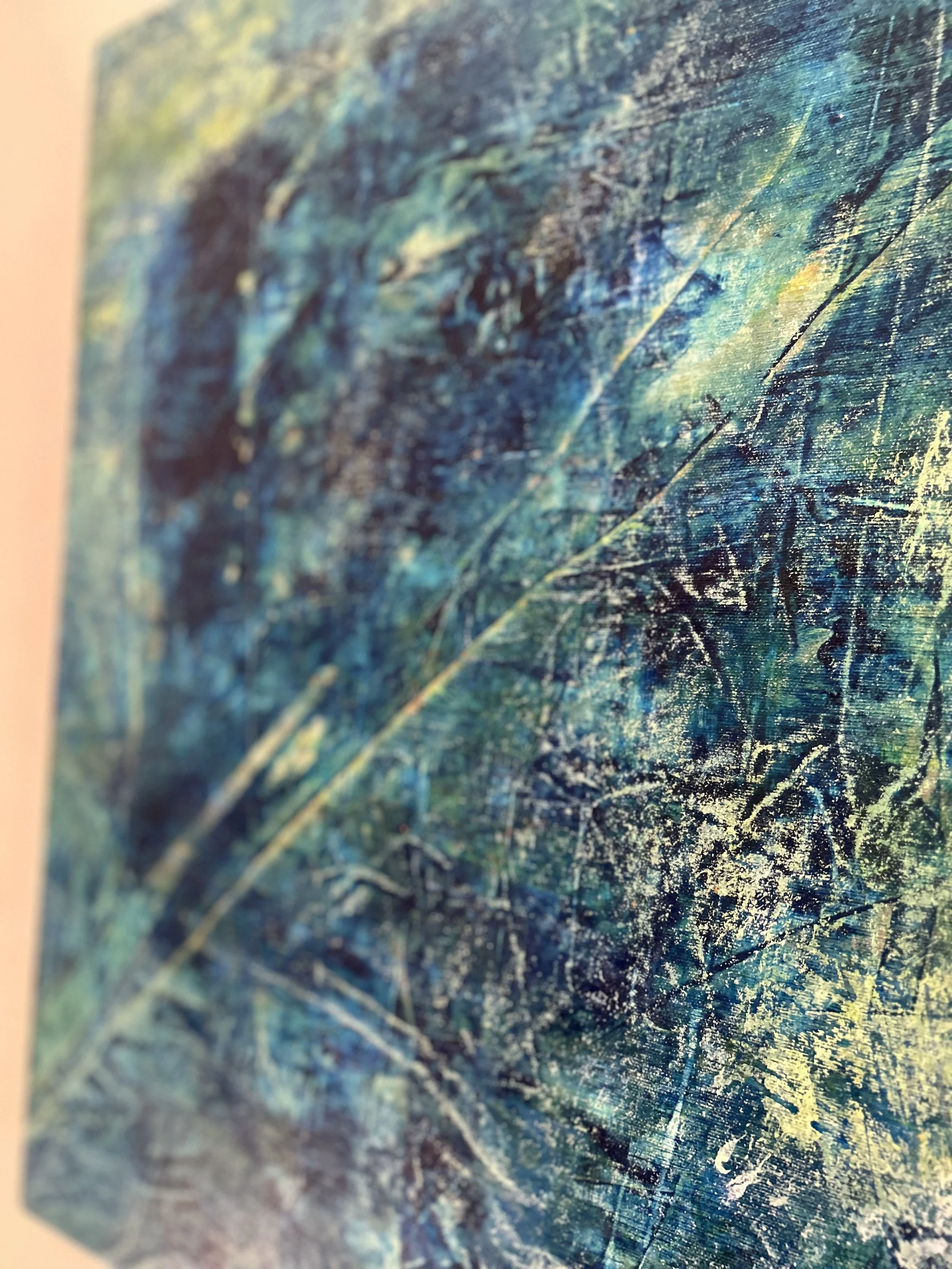 Close-up of an abstract textured painting with streaks, scratches, and splatters in shades of blue, green, yellow, and black.