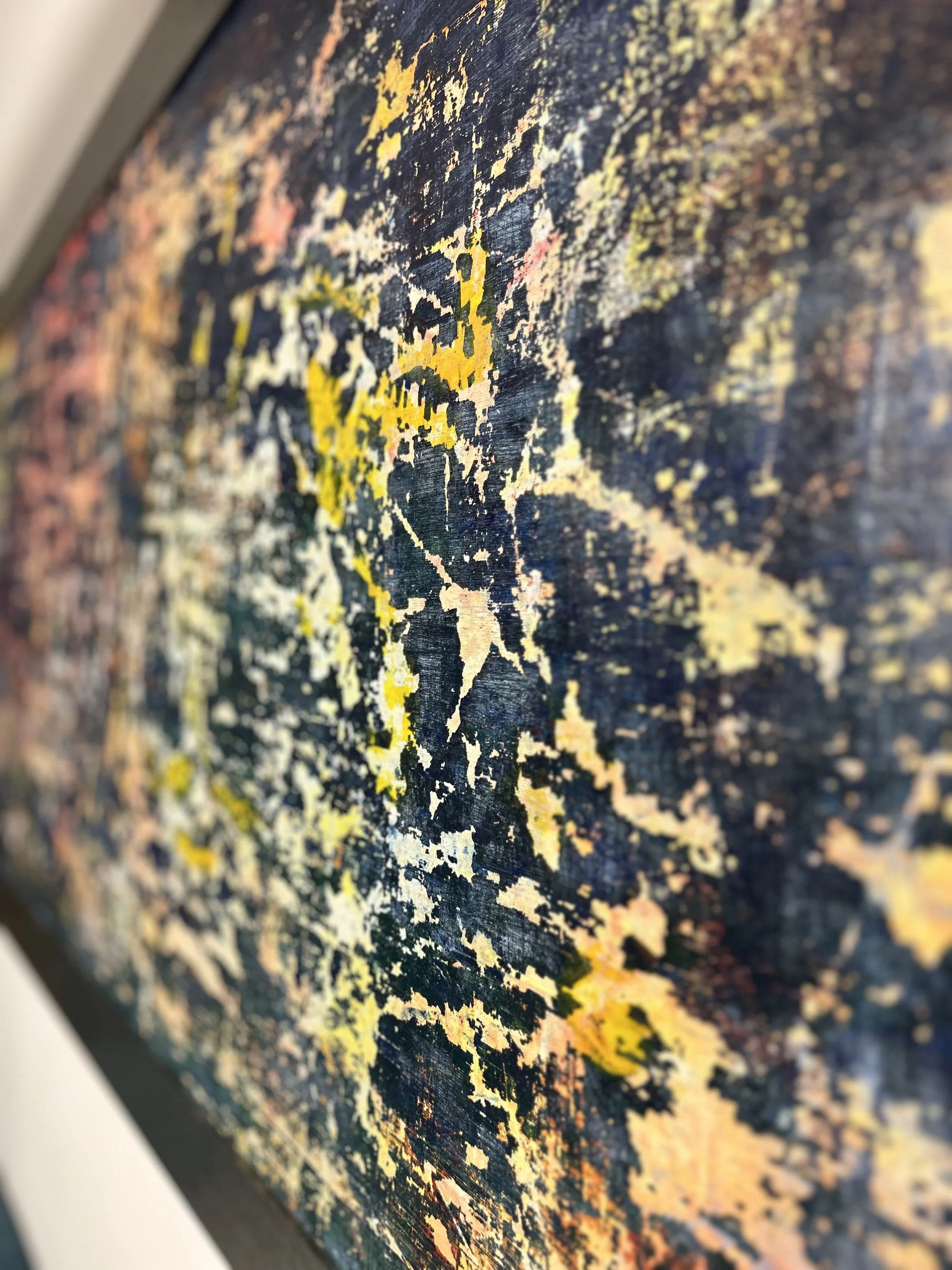 An abstract painting with splashes of yellow, orange, pink, white, and dark colors on a textured surface.