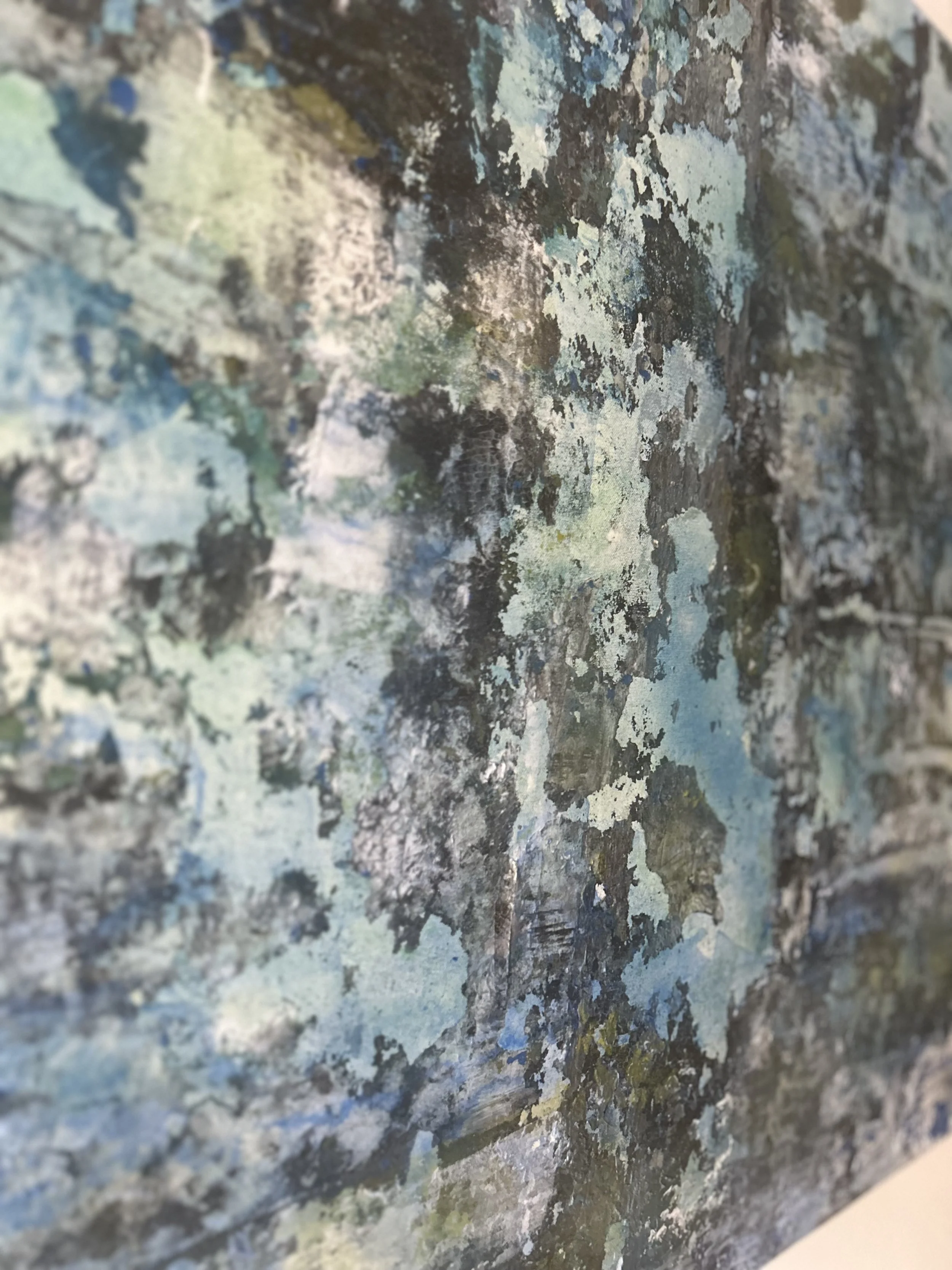 Close-up of a wall with peeling, weathered paint in shades of blue, green, gray, and black, with patches of lichen or moss.