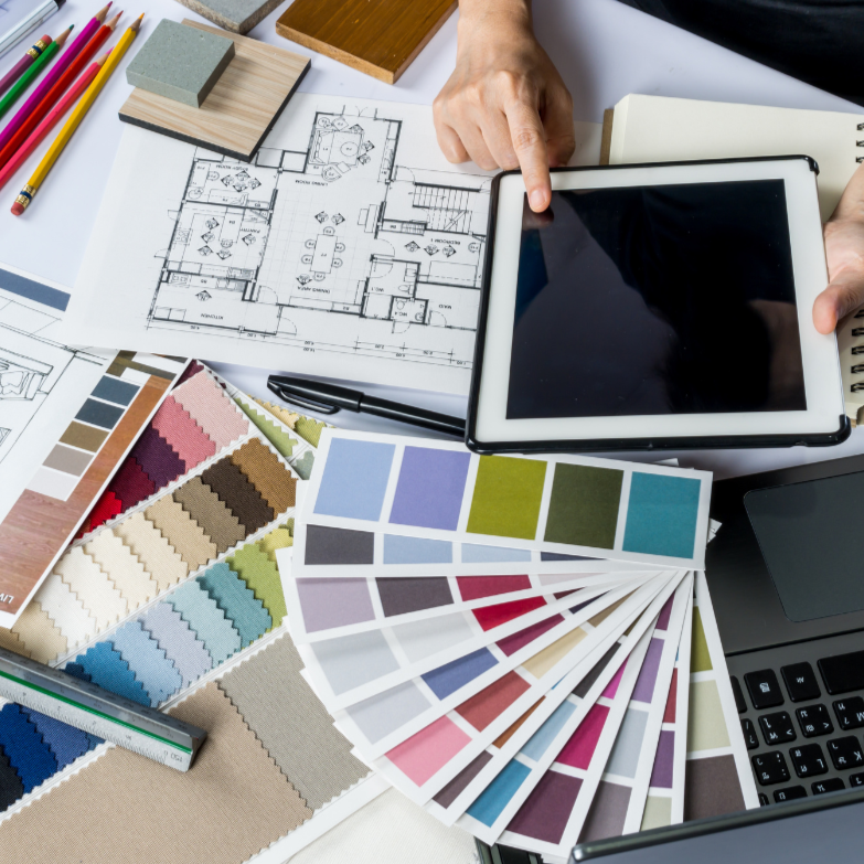 Architectural workspace with floor plan, color swatches, fabric samples, and design tools.