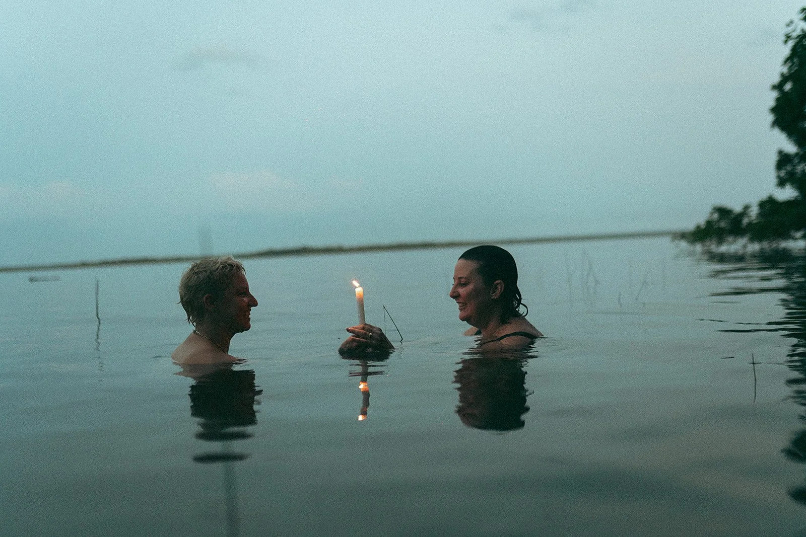 Dos mujeres en el agua, una de ellas sosteniendo una vela