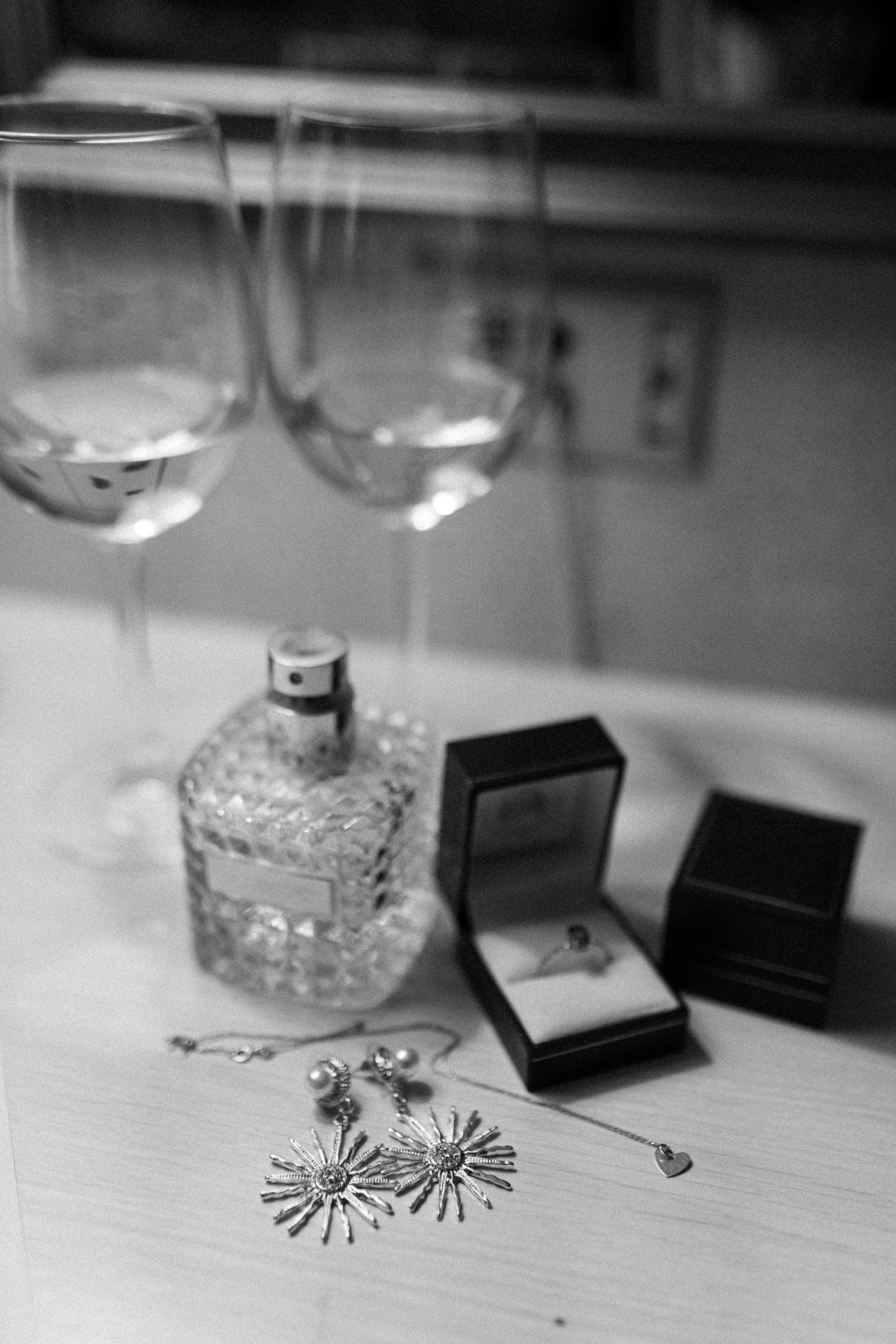 Joyas, en algunos casos con formas de flores o estrellas, y algunos perfumes y cosméticos en su interior en una superficie de madera.