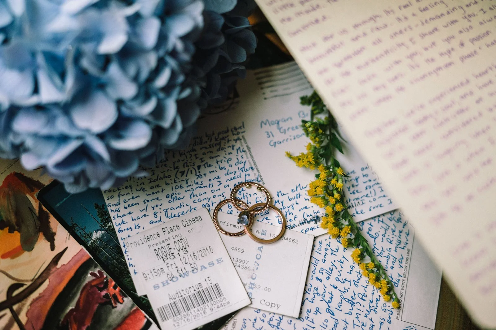 Cartas, boletos, anillos y flores en una mesa.