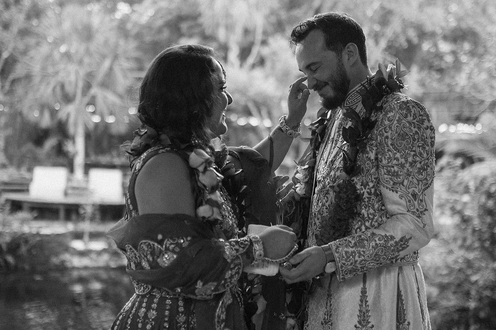 Una pareja en un momento emotivo durante una ceremonia al aire libre, ambos luciendo vestidos tradicionales con decoración floral.