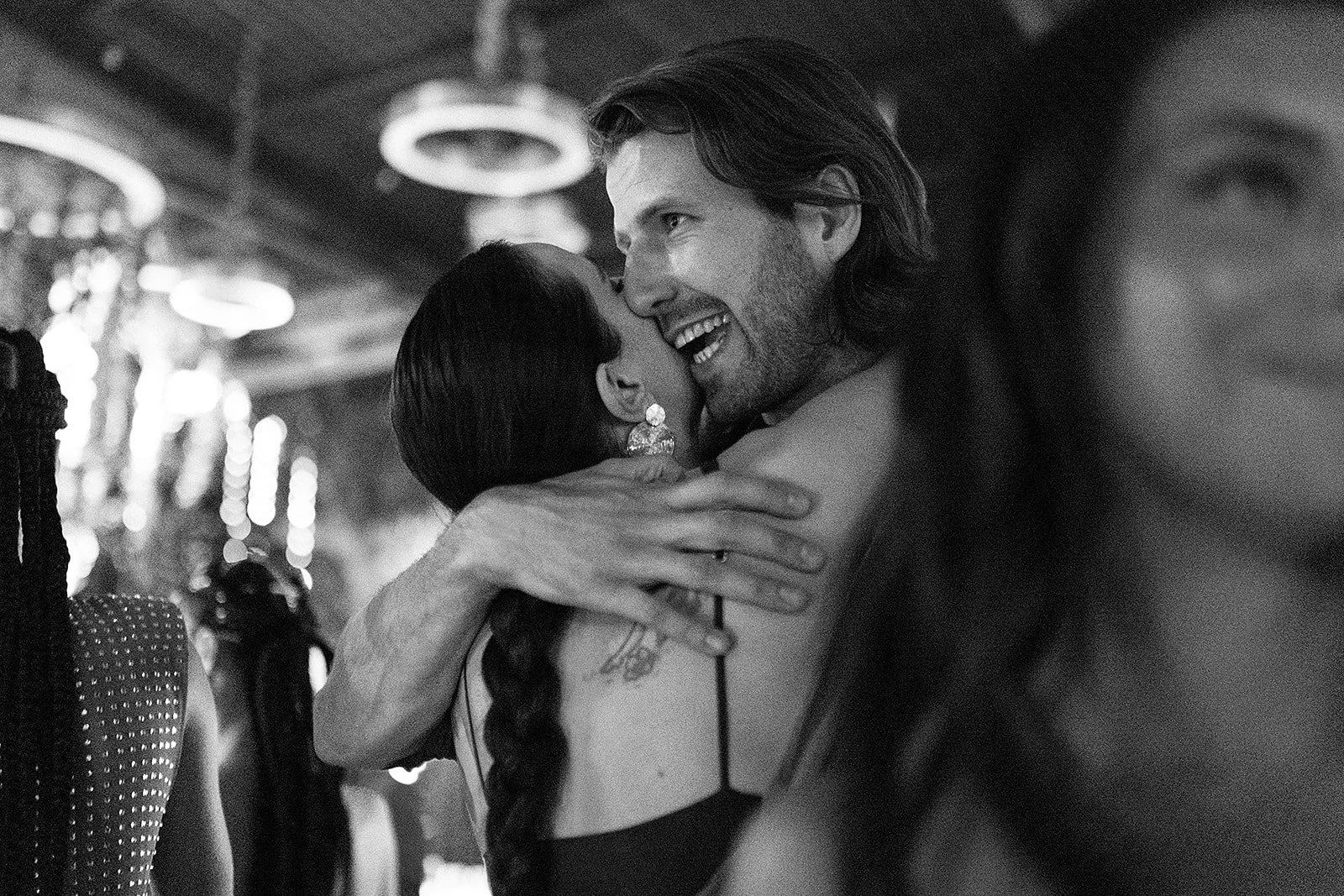 Pareja abrazándose y sonriendo en una escena íntima en un ambiente iluminado, en blanco y negro.