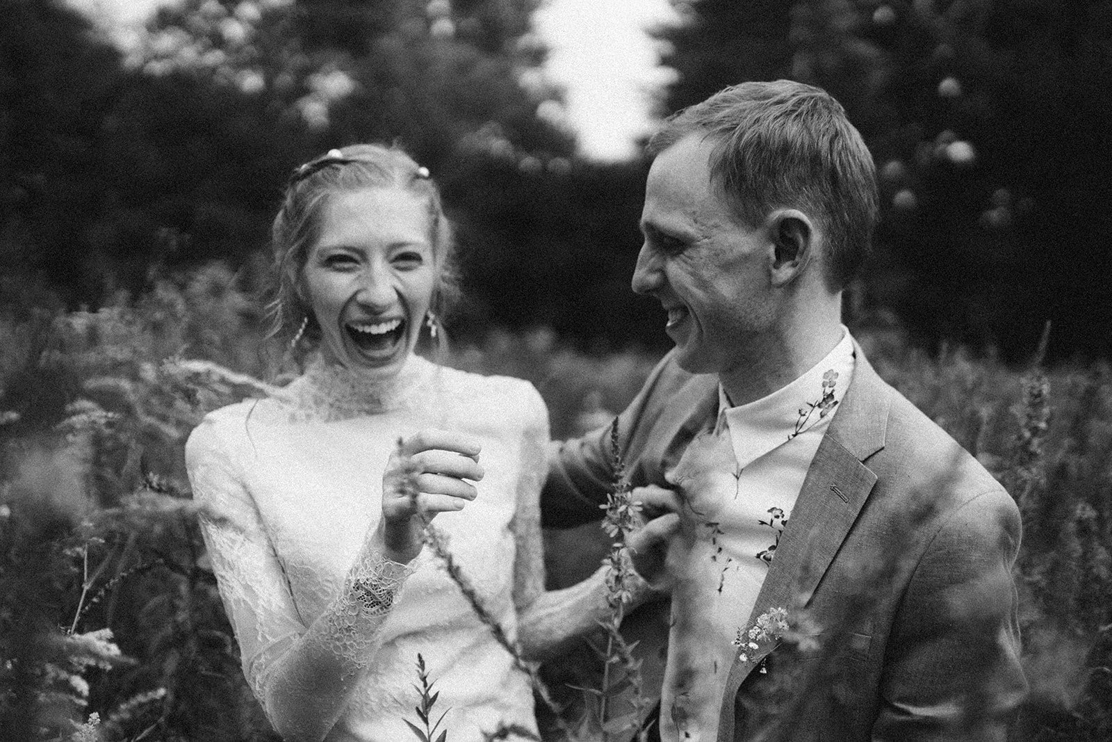 Una pareja riendo y disfrutando en un entorno natural, probablemente durante una celebración casual o boda al aire libre.