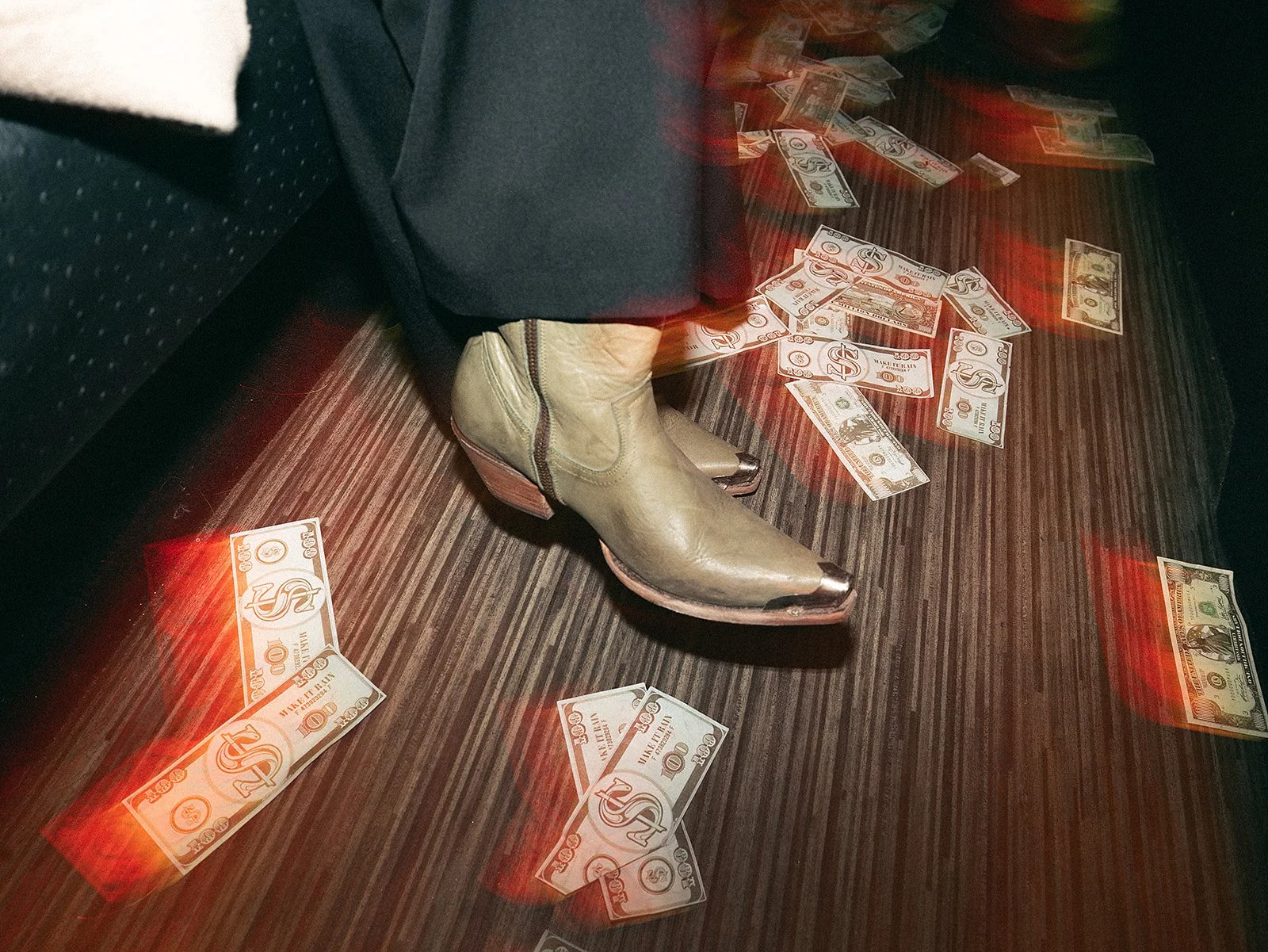 Zapatos de tacón beige con detalles de metal en un suelo de madera, con billetes de dinero de Estados Unidos esparcidos alrededor y reflejos de luces rojas.