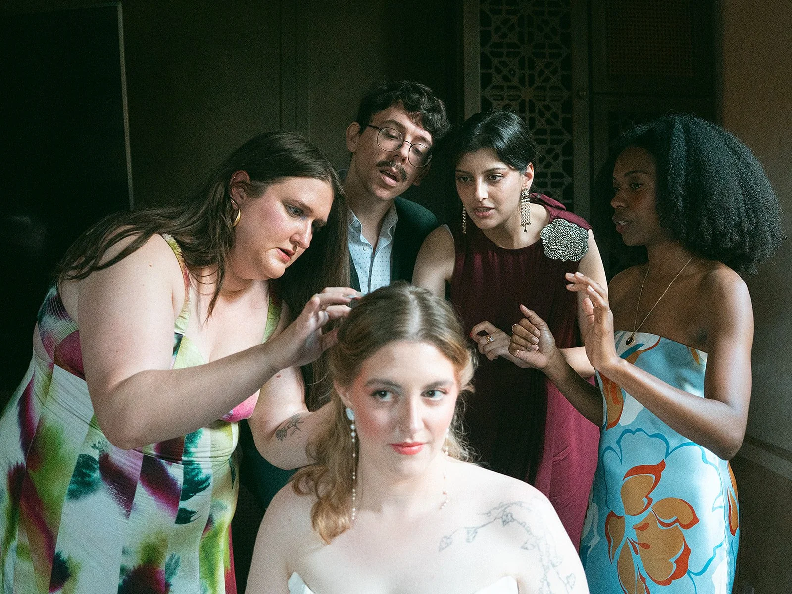 Grupo de personas en una sesión de peinado y maquillaje para una sesión fotográfica o evento, con una mujer rubia en el centro y cinco personas alrededor de ella.