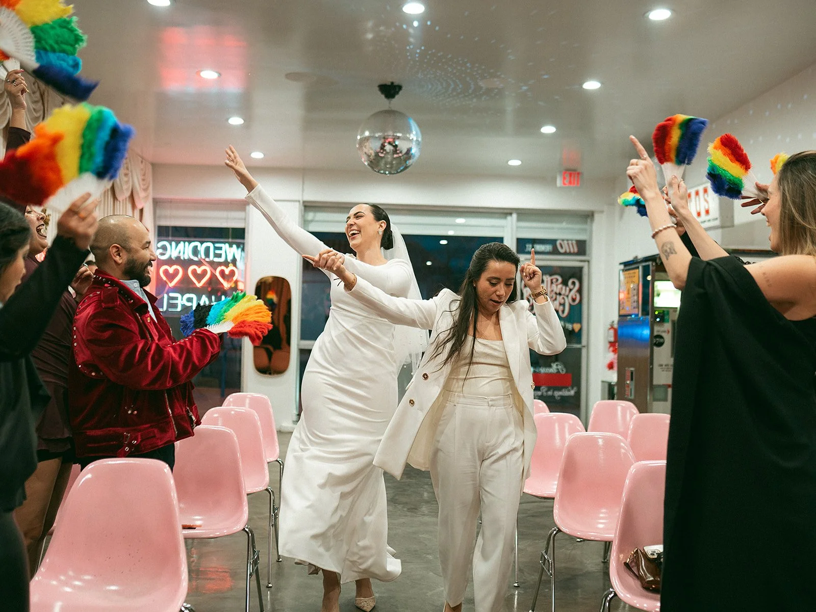 Personas bailando y celebrando en un salón decorado con temática LGBT, con banderas del arcoíris y decoraciones coloridas.