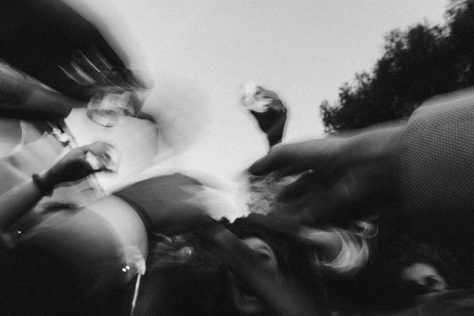 Personas en una reunión o fiesta, algunas con bebidas, en un ambiente oscuro y borroso, imagen en blanco y negro.