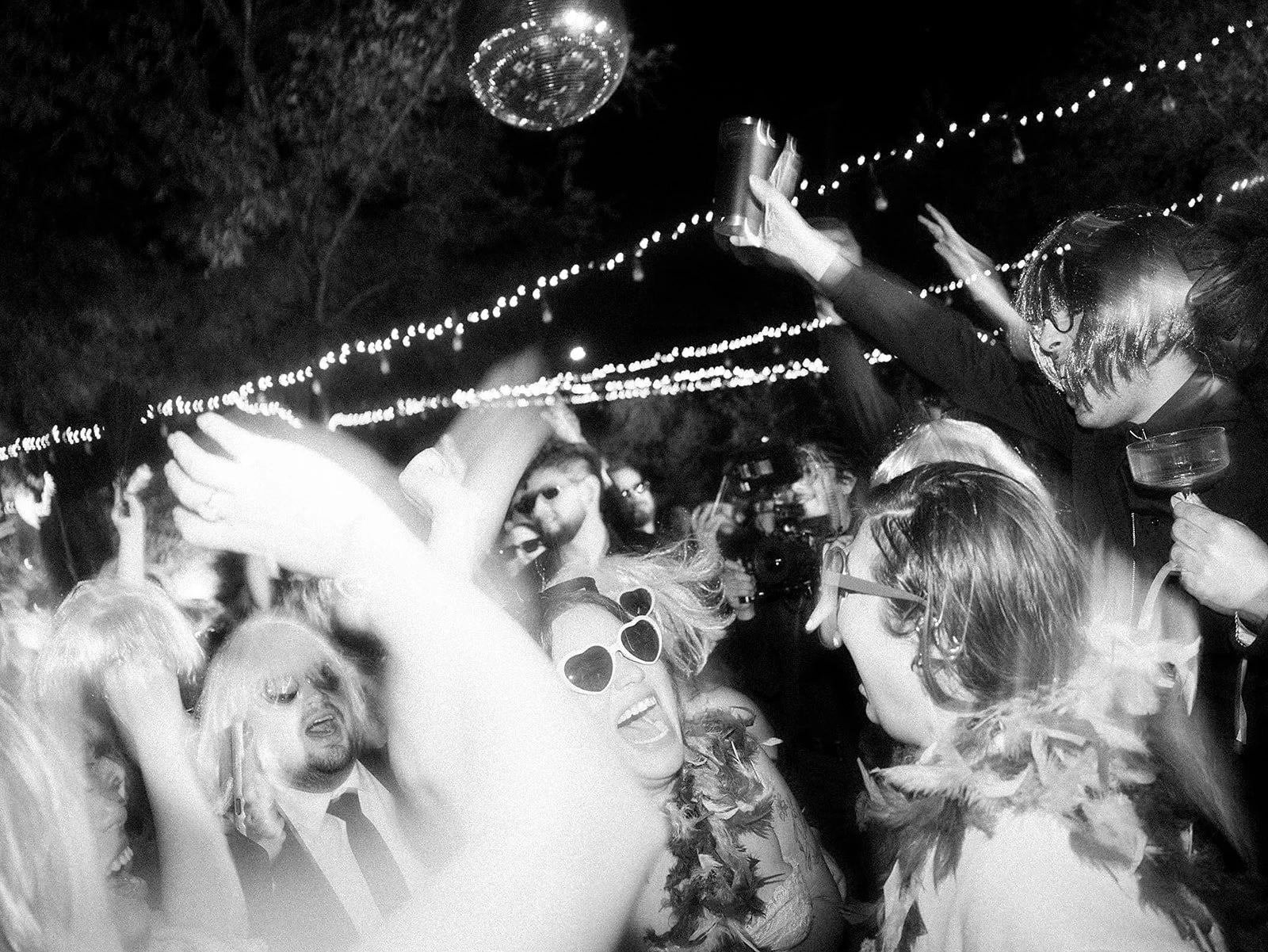 Gente bailando en una fiesta nocturna con luces y decoración festiva.