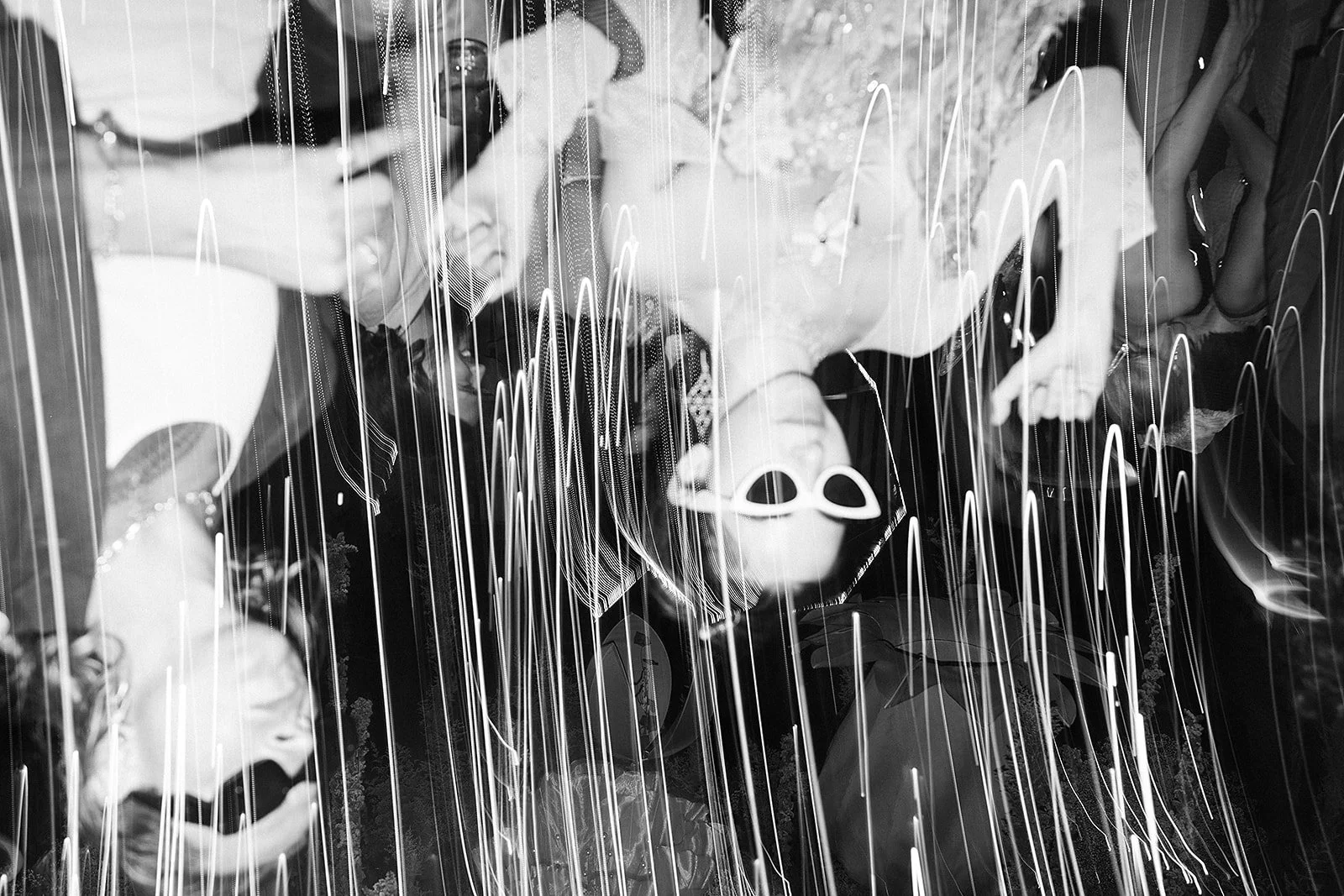 Personas en una celebración, algunas con globos y accesorios decorativos, en una imagen en blanco y negro con líneas de luz decorativas.