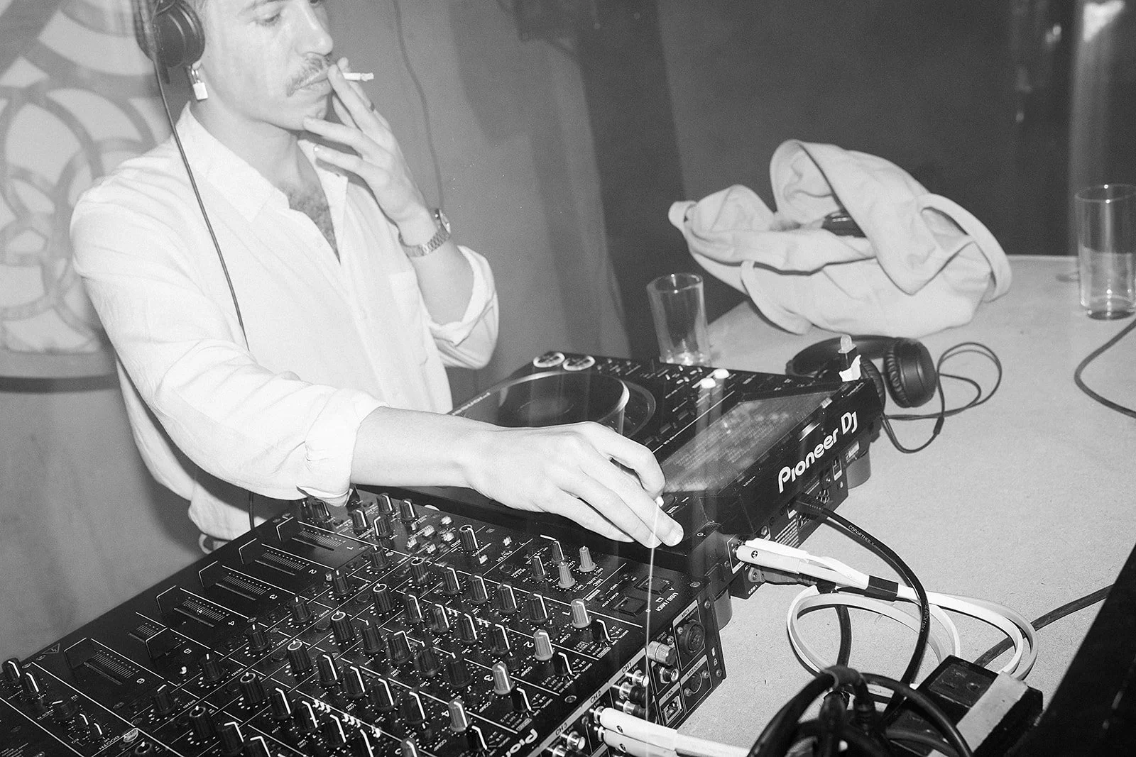 Hombre con auriculares en un equipo de DJ en un ambiente de discoteca o evento.